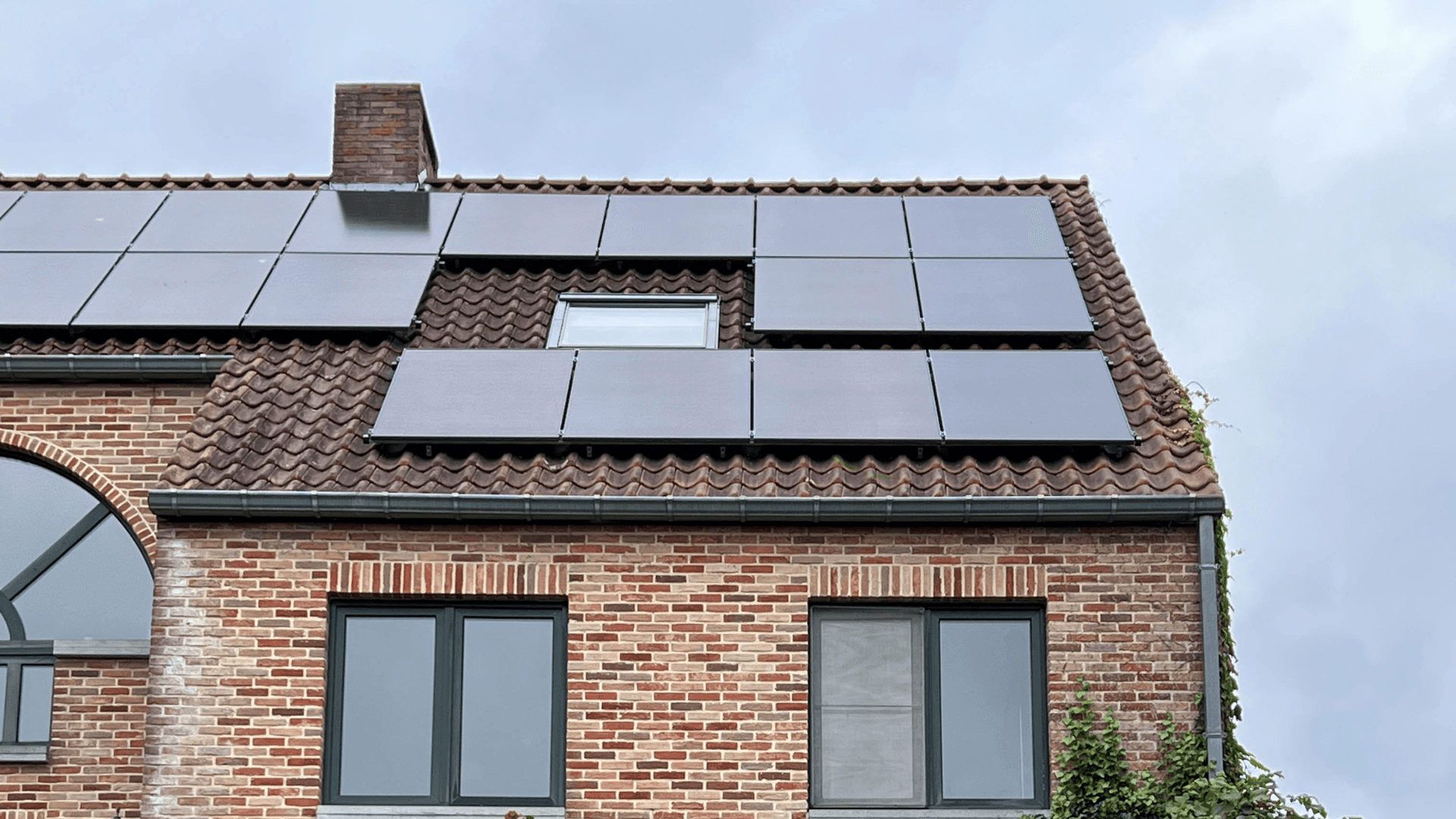 Ein modernes Gebäude mit auf dem Dach installierten Solarpaneelen unter einem bewölkten Himmel.