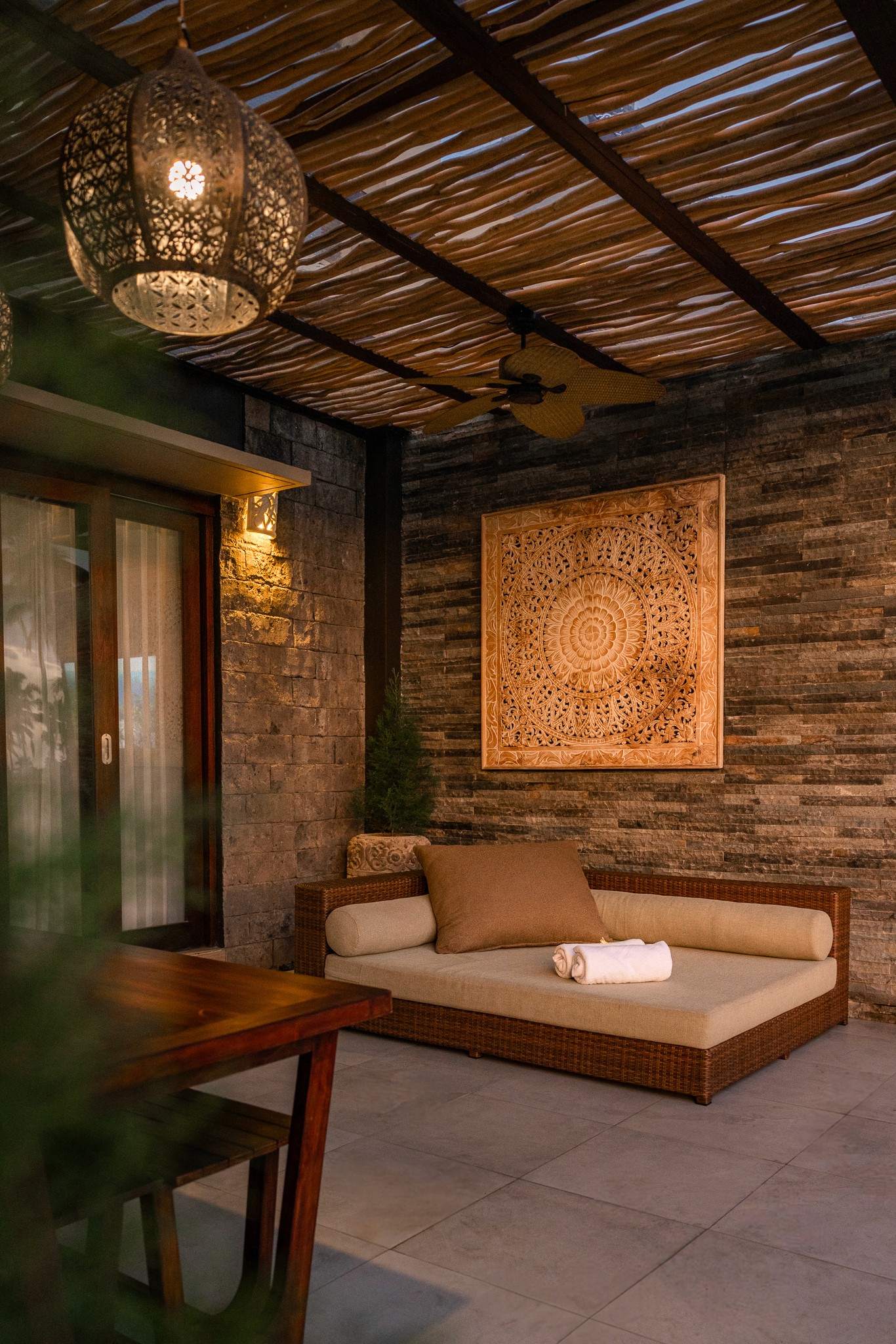 Gemütliche Sitzecke mit Natursteinwand und kunstvollem Dekor – Luxuriöse Einrichtung in den Khastana Hadi Villas, Bali