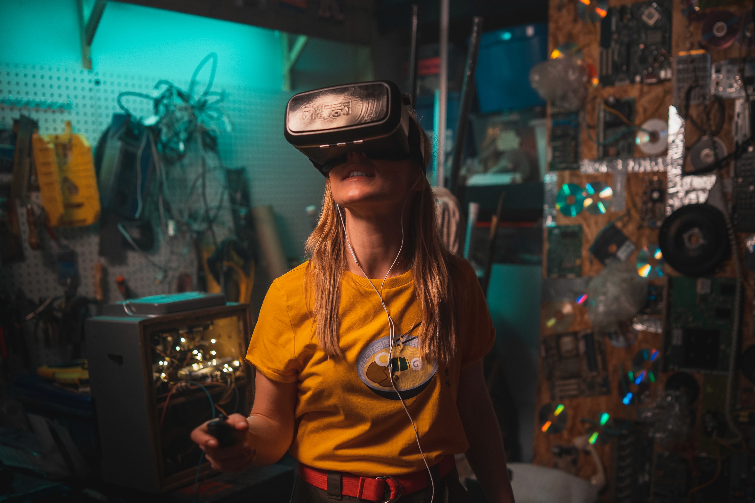 Une jeune fille dans une pièce surchargée d'objets technologiques porte un casque de réalité virtuelle.