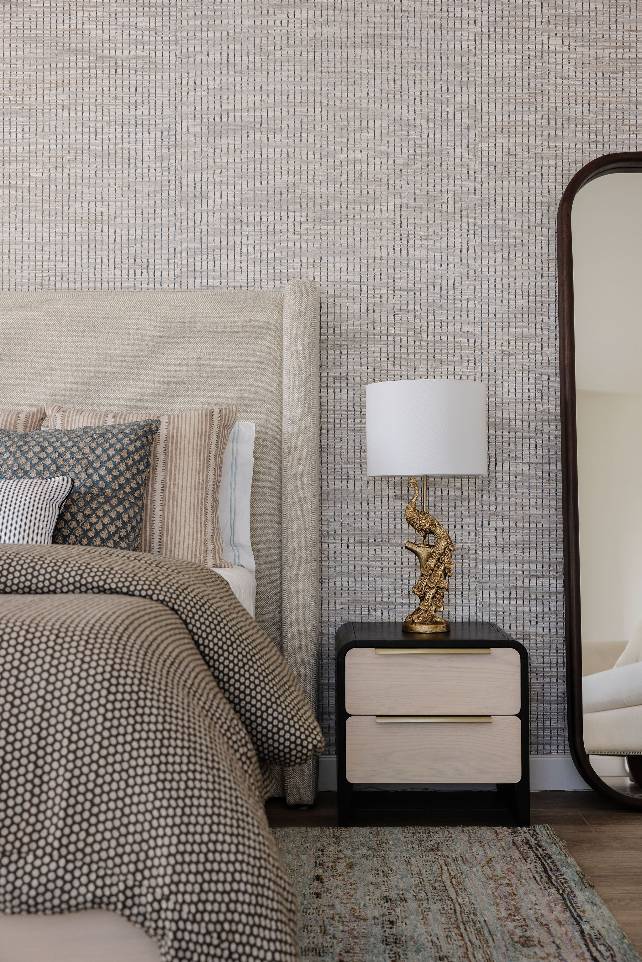 Relaxing bedroom with layered linens, textures, and tones, and a large mirror.
