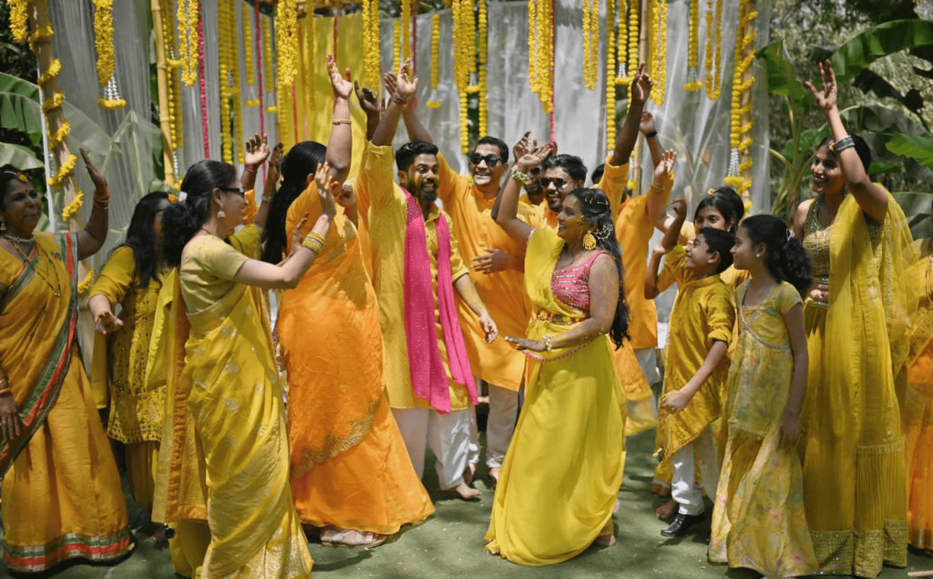 Joyful Indian wedding haldi ceremony with family and friends in vibrant yellow attire.