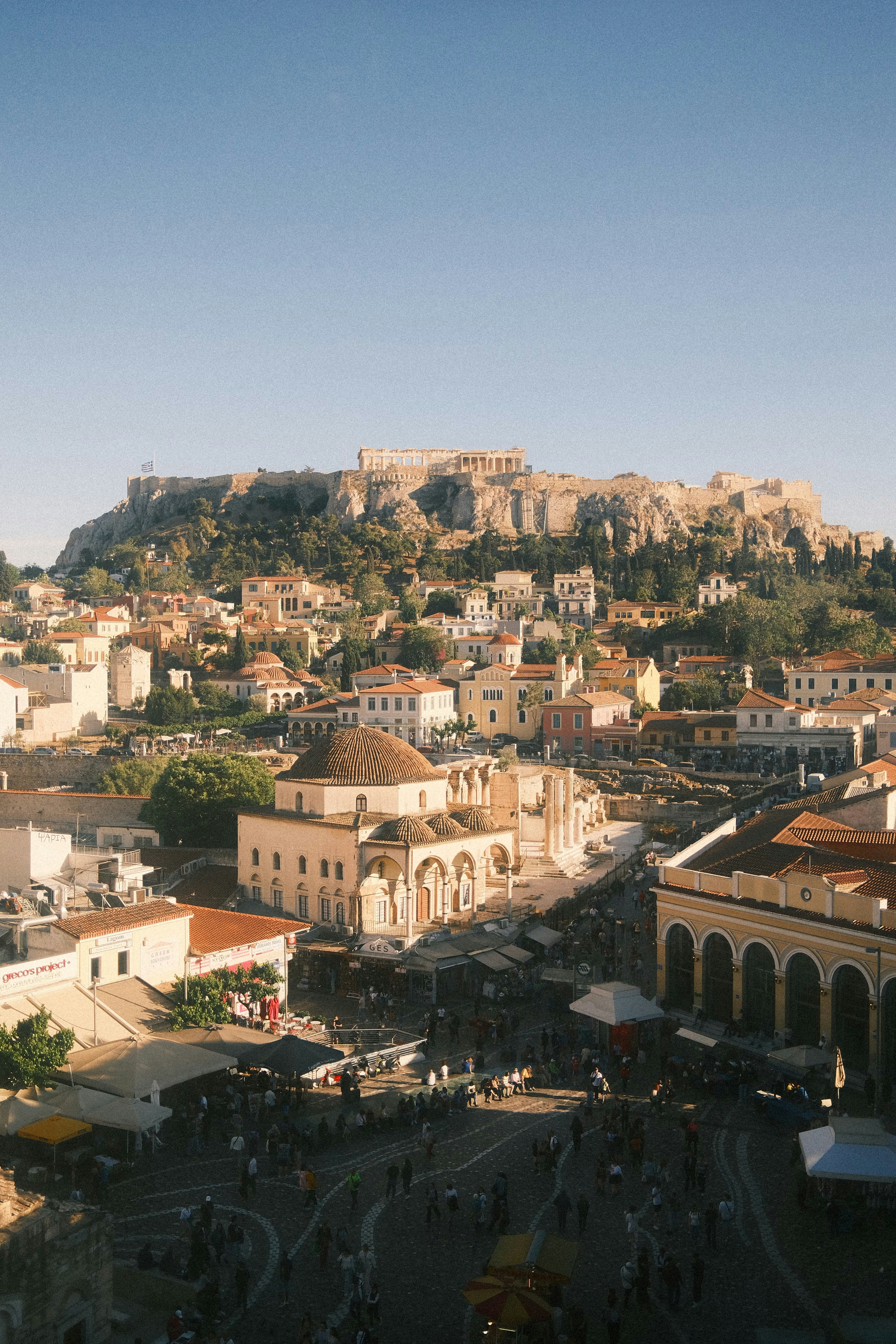 a street lined with stone buildings next to a lush green forest