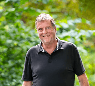 A person standing outdoors with trees in the background.