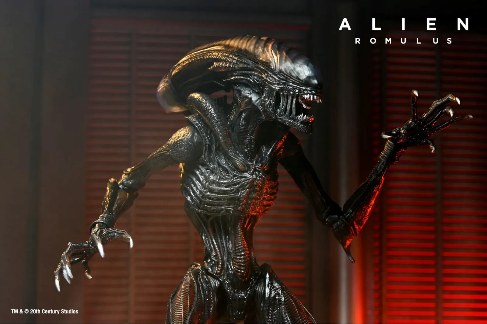 A menacing, intricately detailed extraterrestrial creature with sharp claws and an elongated head stands in a dark, atmospheric setting, illuminated by red lighting, promoting the film "Alien Romulus."