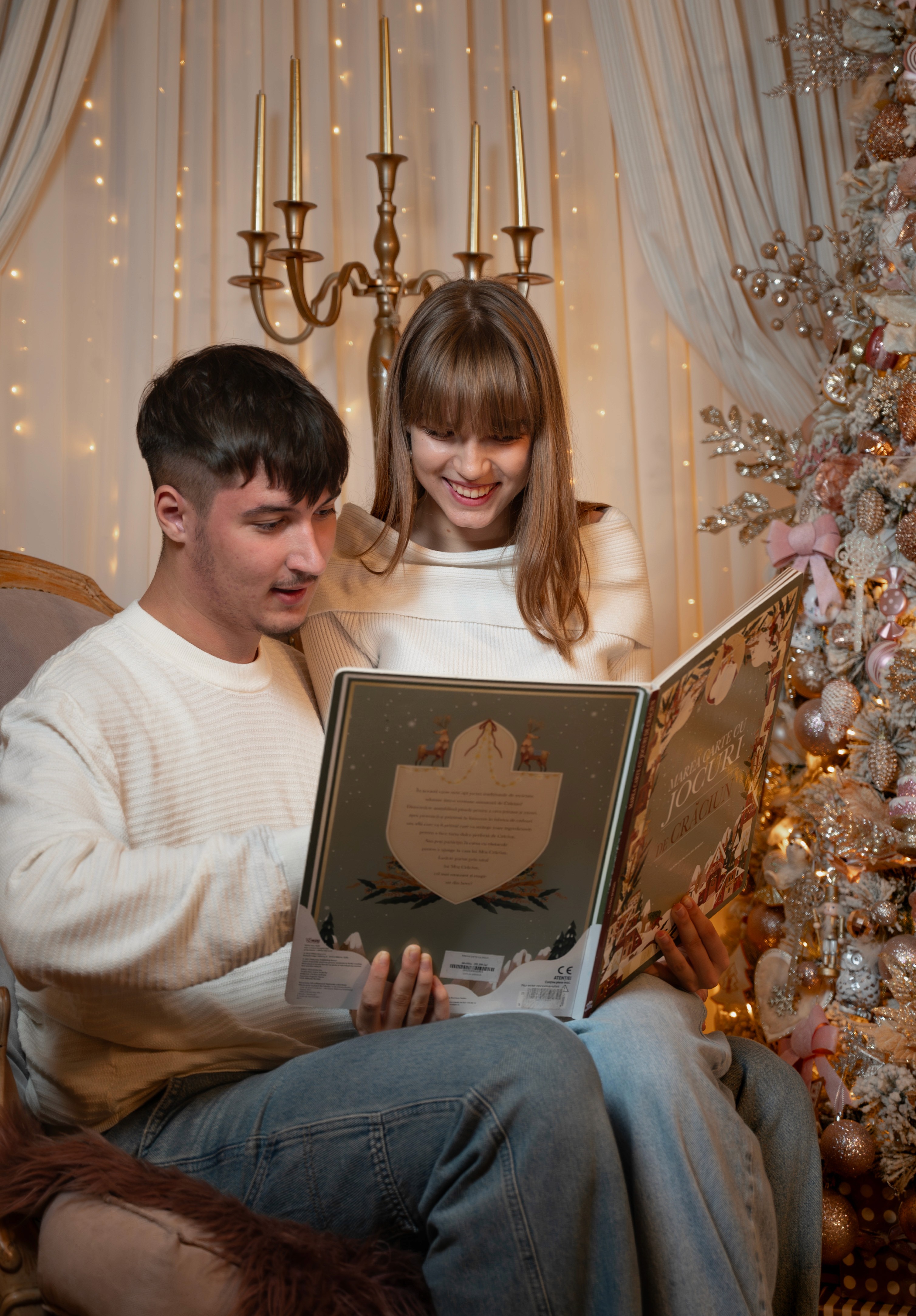 Ședință foto de Crăciun cu cuplu deschizând un album, moment natural și emoționant