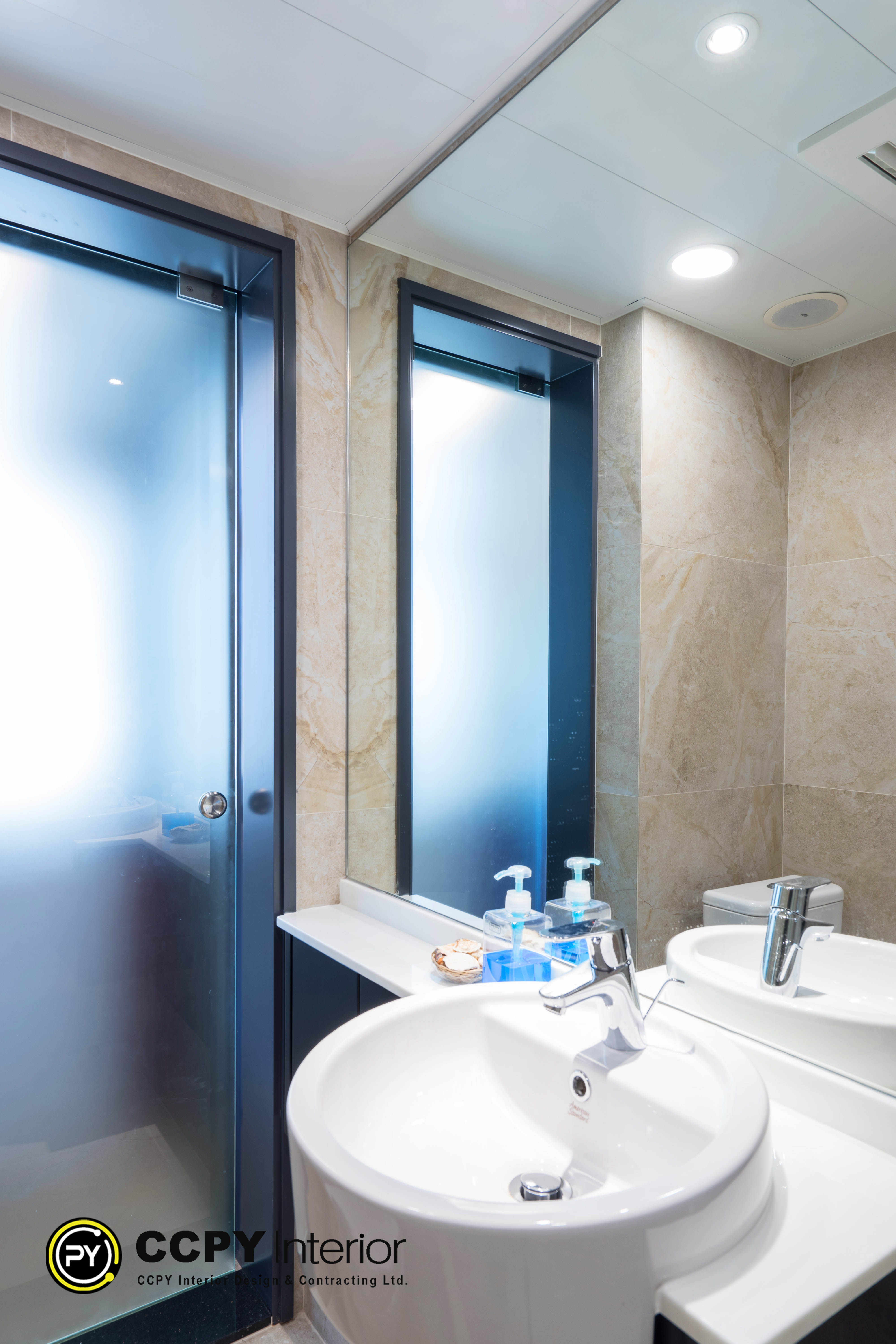 The selected region shows a modern bathroom vanity featuring a sleek rectangular mirror, light beige marble-patterned wall tiles, and blue bathroom accessories on the counter.Key Design FeaturesSmart Luxury Theme: Designed to maximize small spaces with a high-fashion look.Intelligent Lighting: The setup features integrated accent lighting around the mirror.Premium Materials: Walls are finished with polished beige stone or porcelain tiles.Modern Fixtures: Includes a minimalist chrome faucet and frosted glass shower door panels.