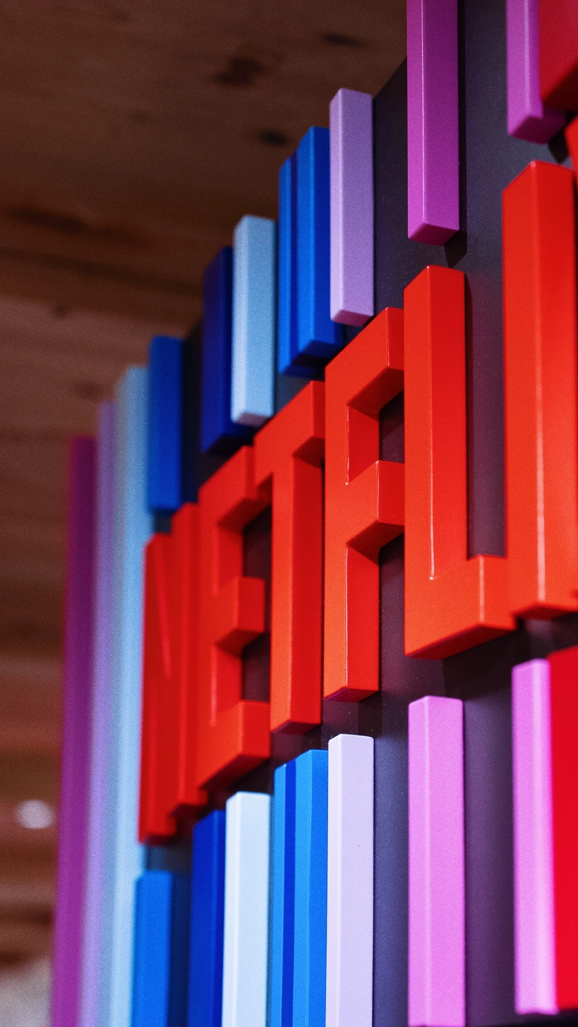 Close-up of a Netflix 3D wall installation made from vertical pixel-style strips in red, blue, pink and purple forming the Netflix wordmark.