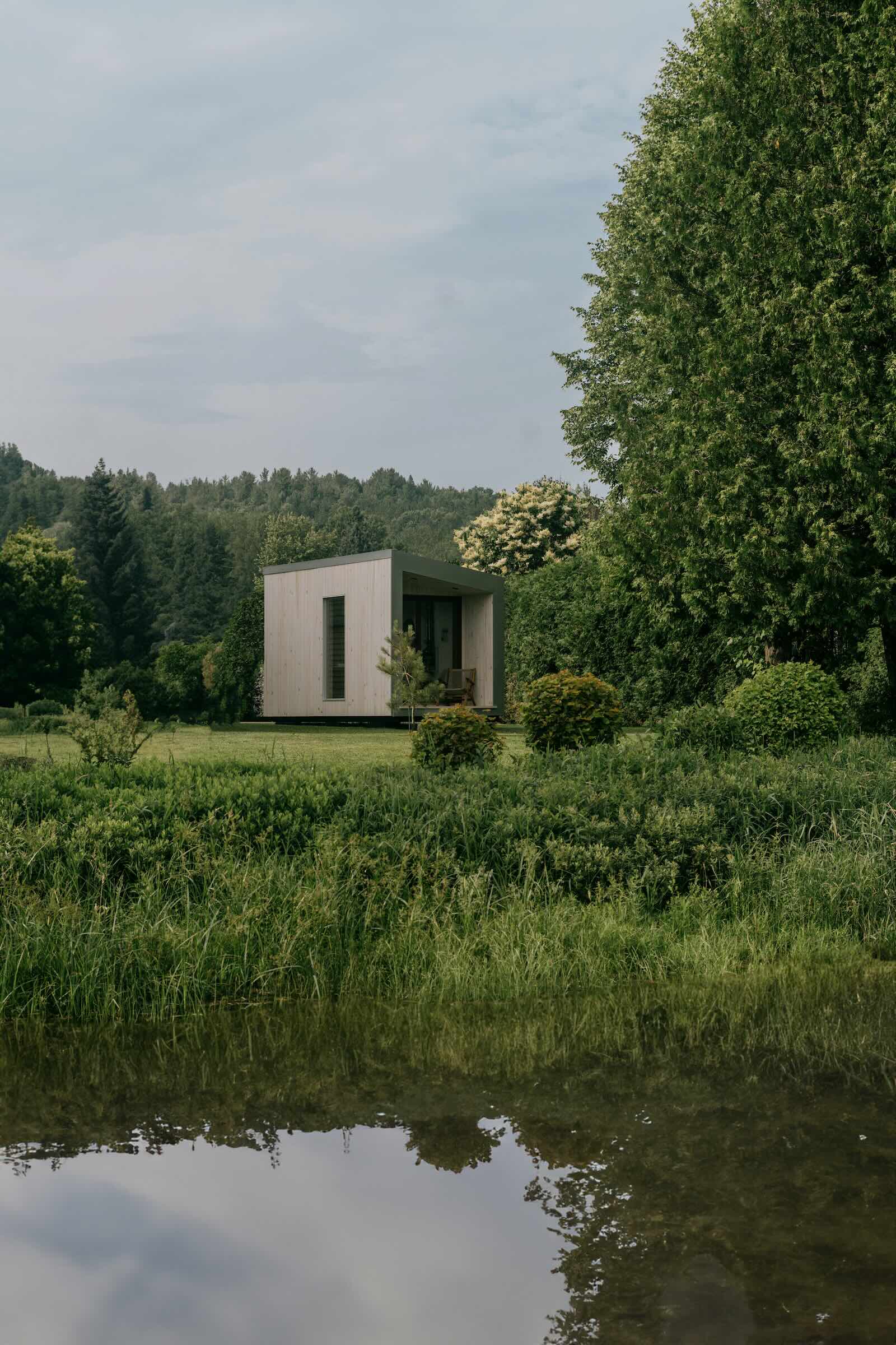 Petite construction moderne au bord d’un plan d’eau entouré de végétation