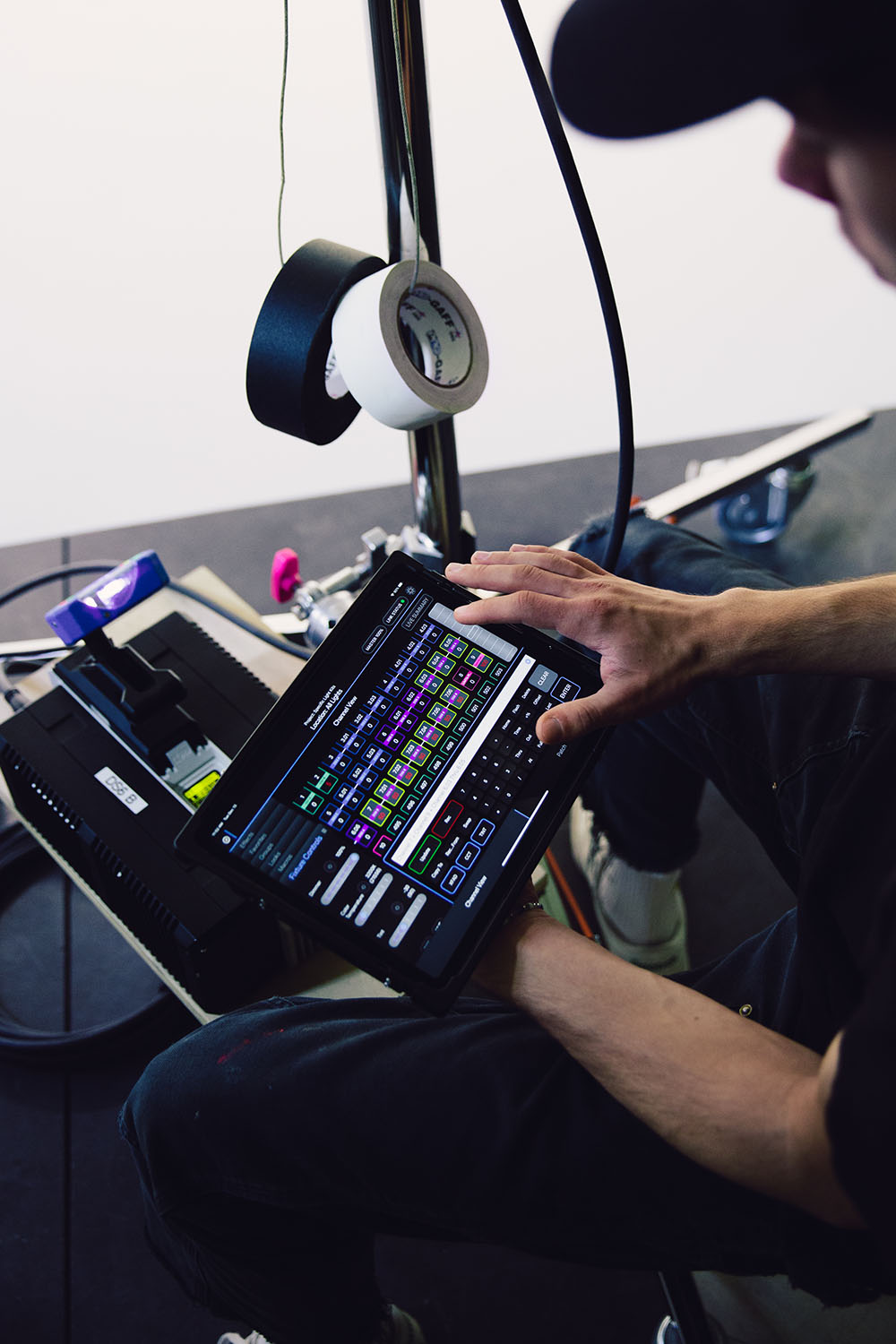 A gaffer adjusts lighting fixtures on an Ipad equipped with Black Out Lighting Console