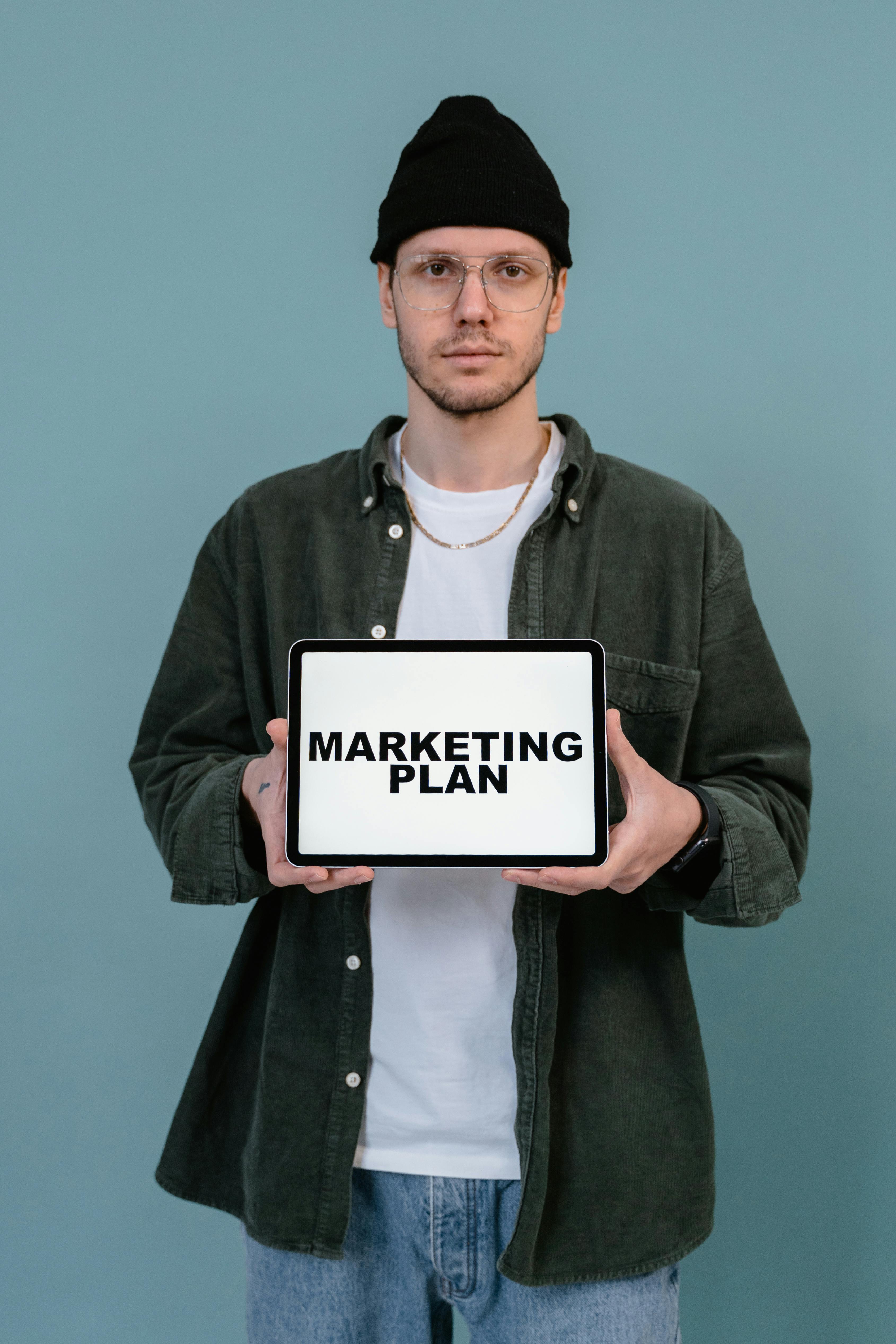 A person holding whiteboarding written Marketing Plan - Digital Marketing for Prop Firms