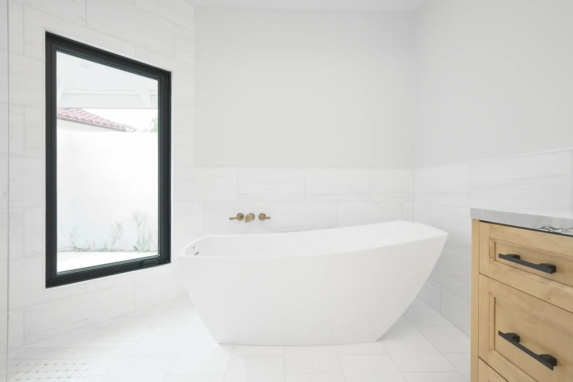 Wide view of the primary bathroom, featuring a luxurious walk-in shower and elegant free-standing tub and custom vanity with quartzite countertop, embodying opulence and modern design in the Dana Point Full Remodel. Photo by Todd Huge.