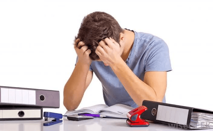 High school student sitting at a desk surrounded by research papers and books, looking exhausted and overwhelmed