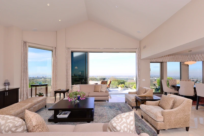 Luxurious living space with large windows offering city views in Harbor Ridge Transitional Remodel.
