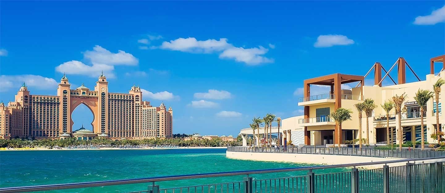 Luxury waterfront villas and residential properties on one of the Palm Jumeirah fronds, with the sea gently washing the sandy beach.