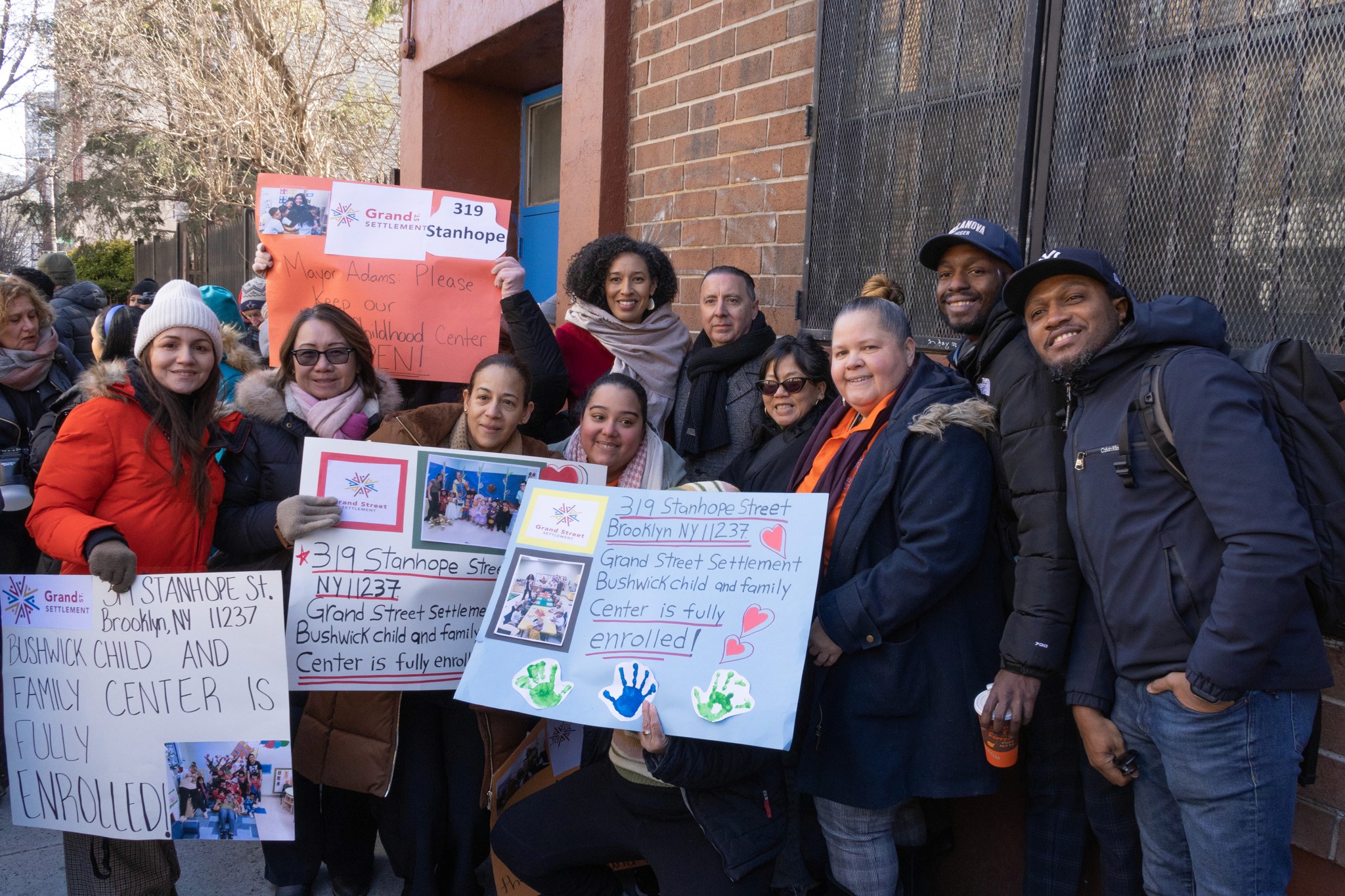 Staff, participants, and elected officials hold signs advocating to save Bushwick Child and Family Center