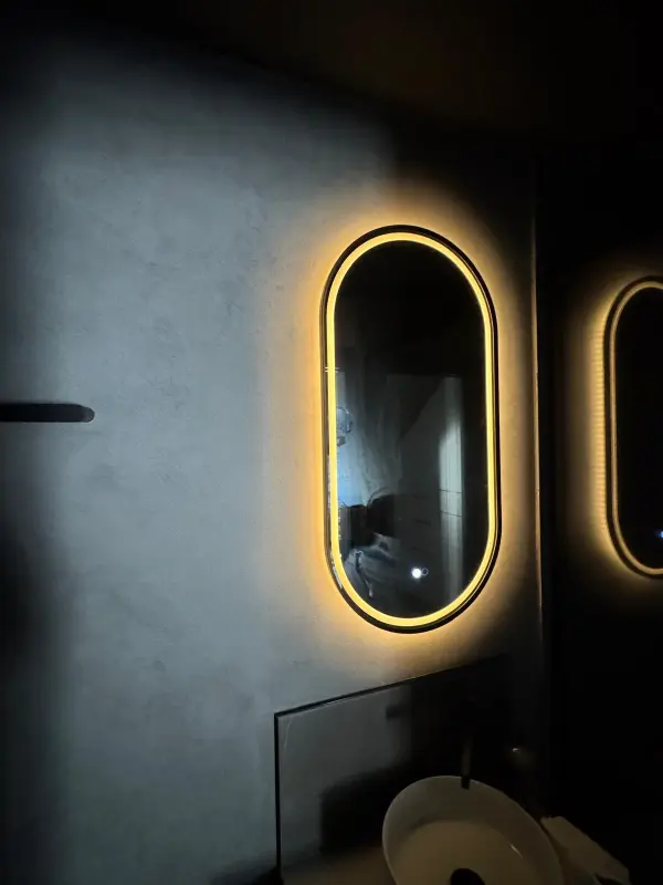 Bathroom vanity with illuminated arched mirror and refined wall finish
