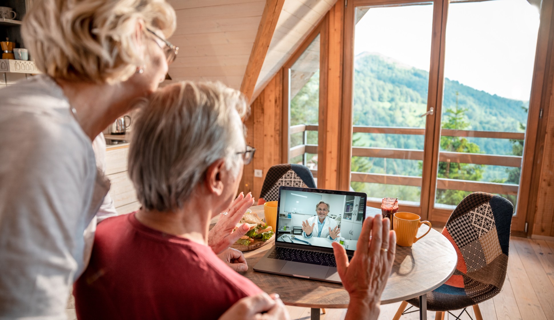 an elderly couple looking at their laptop as they have a telehealth session with their provider