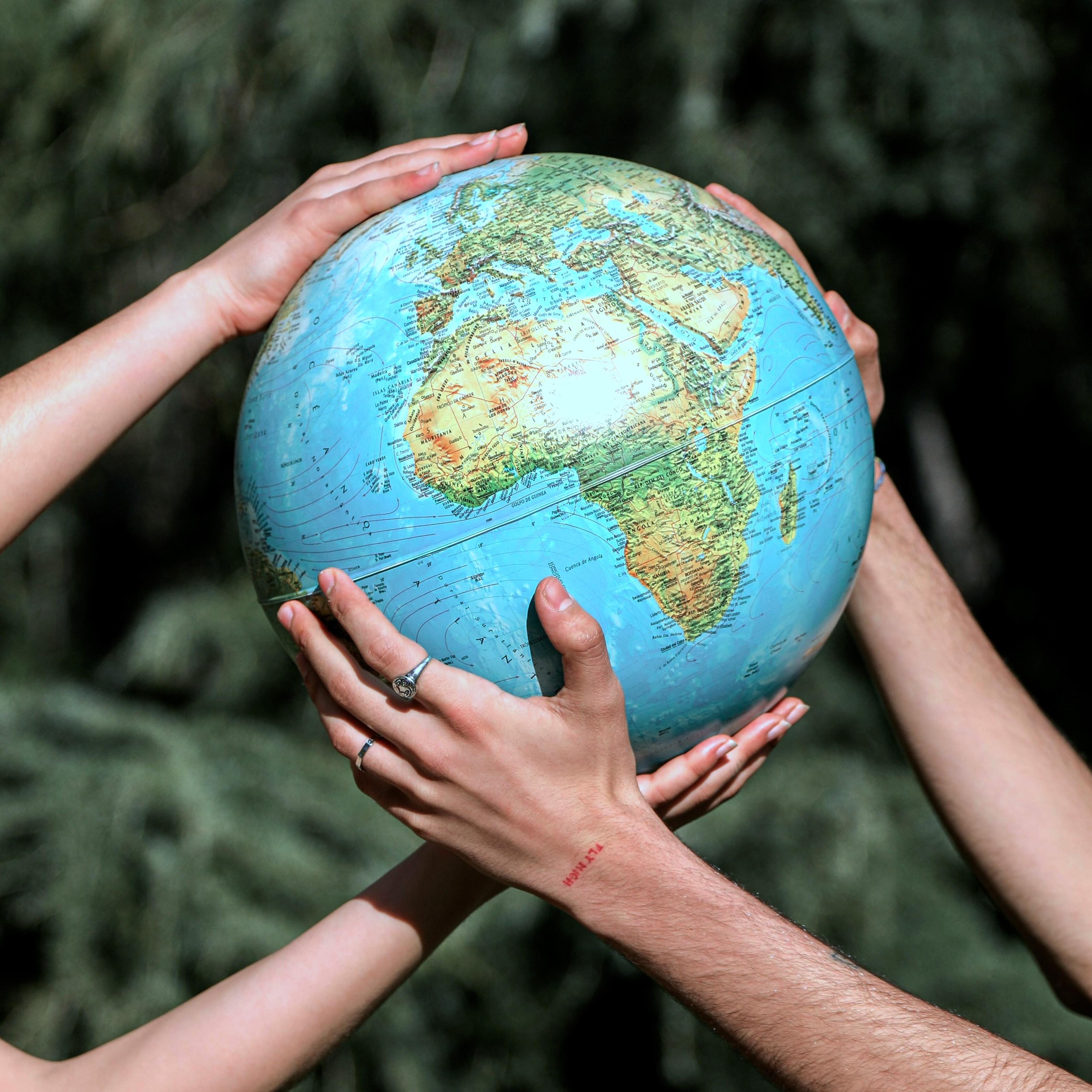 Two sets of hands holding a globe