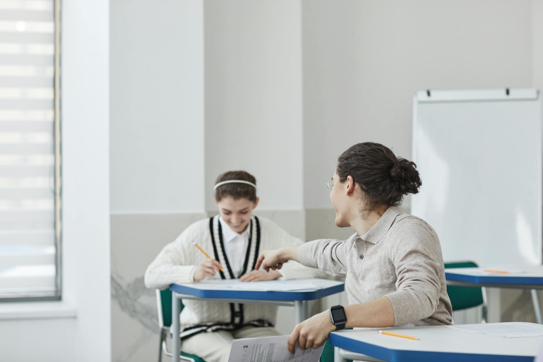Close-up of four students' hands working together to solve a complex math puzzle on a shared desk.