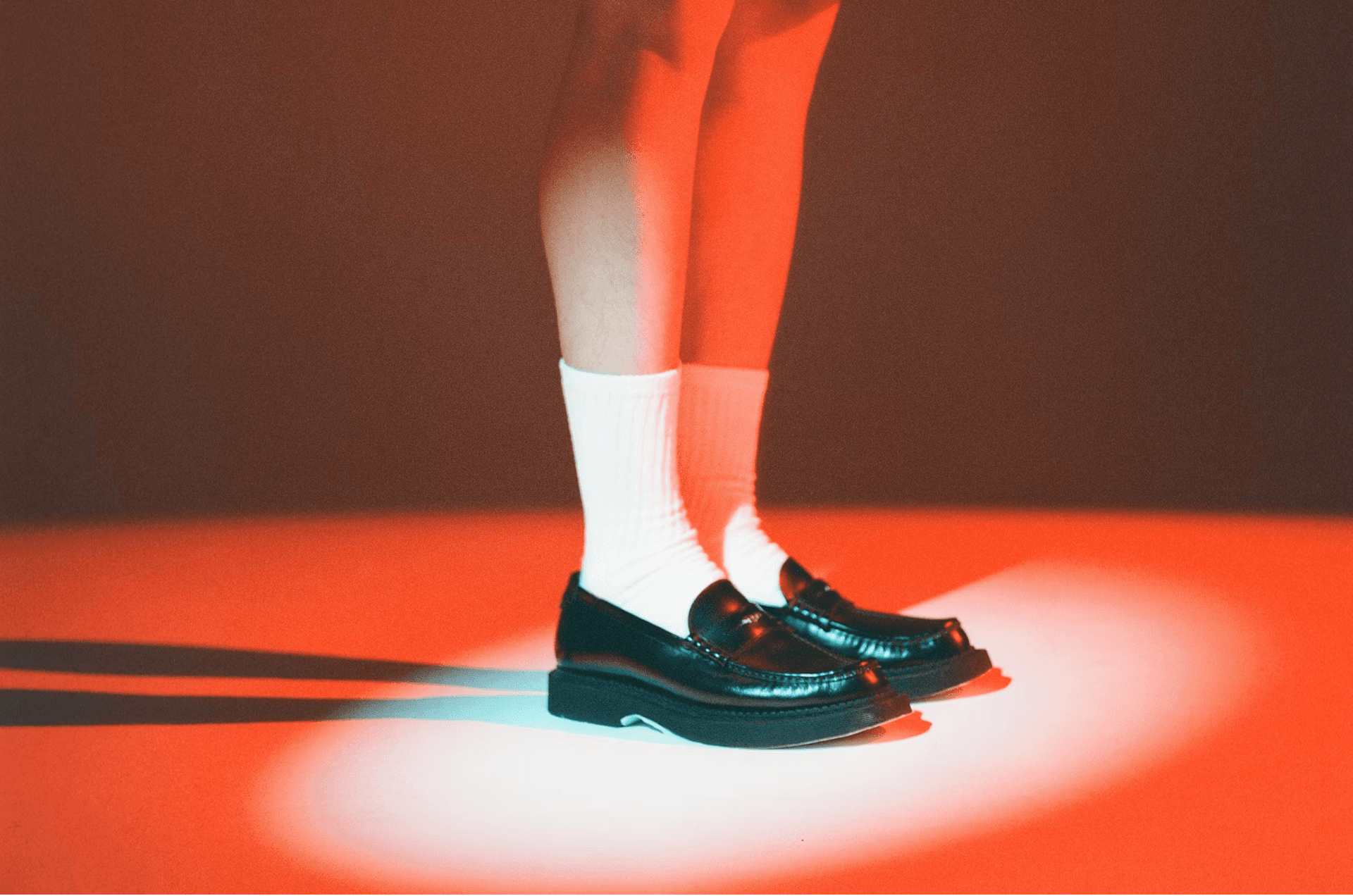 A person standing in a literal spotlight wearing black leather loafers and white crew socks, representing a highlighted B2B website visitor or lead.