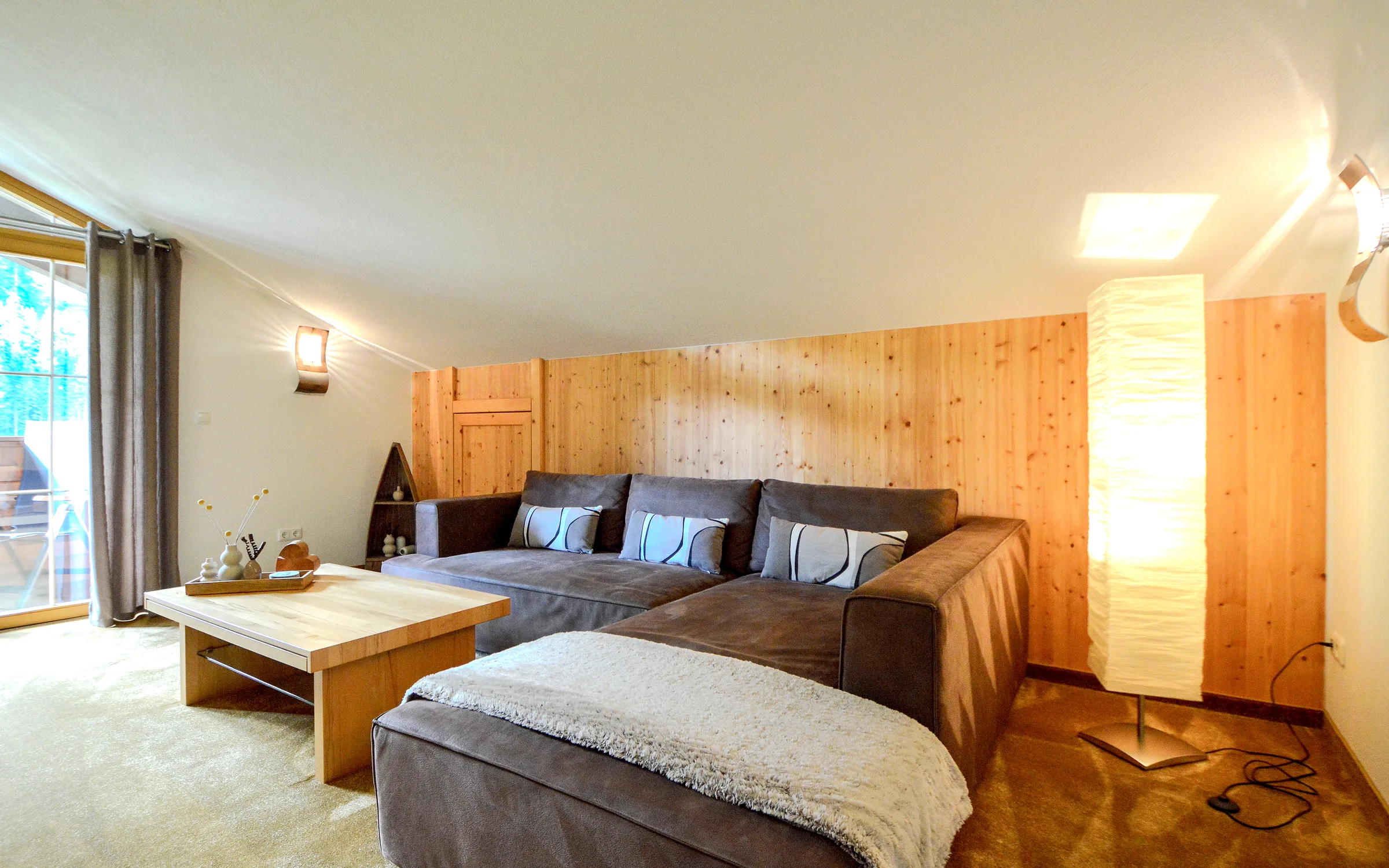 Wohnbereich mit Sofaecke, Couchtisch und Holzvertäfelung im Landhaus Rossberg