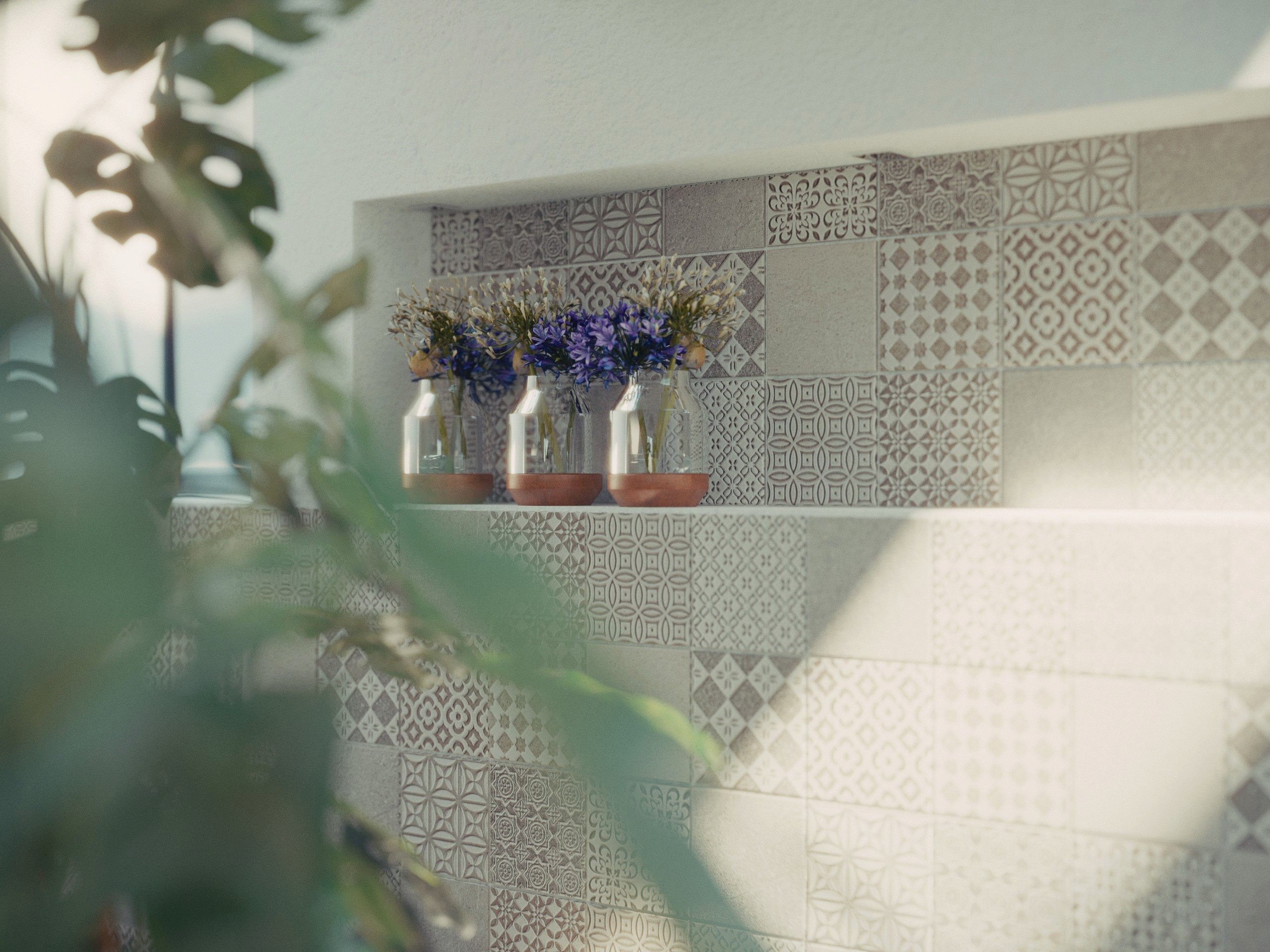 Dettaglio di nicchia con rivestimento in cementine a decori geometrici in rilievo, con vasi di agapanthus viola, atmosfera mediterranea