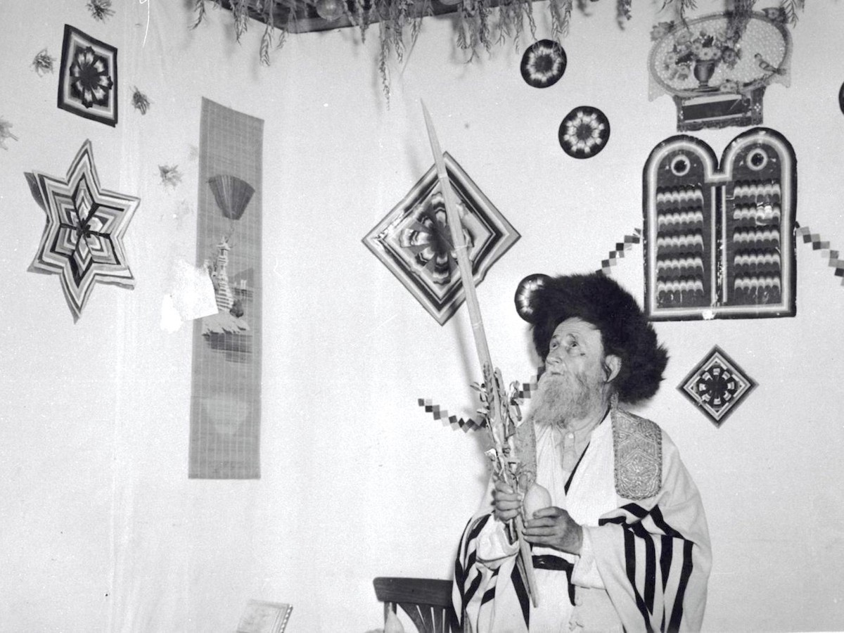 A man performs the mitzvah of the Four Species inside a sukkah in Jerusalem, 1959. Photo courtesy of Avraham Malevsky, KKL-JNF.