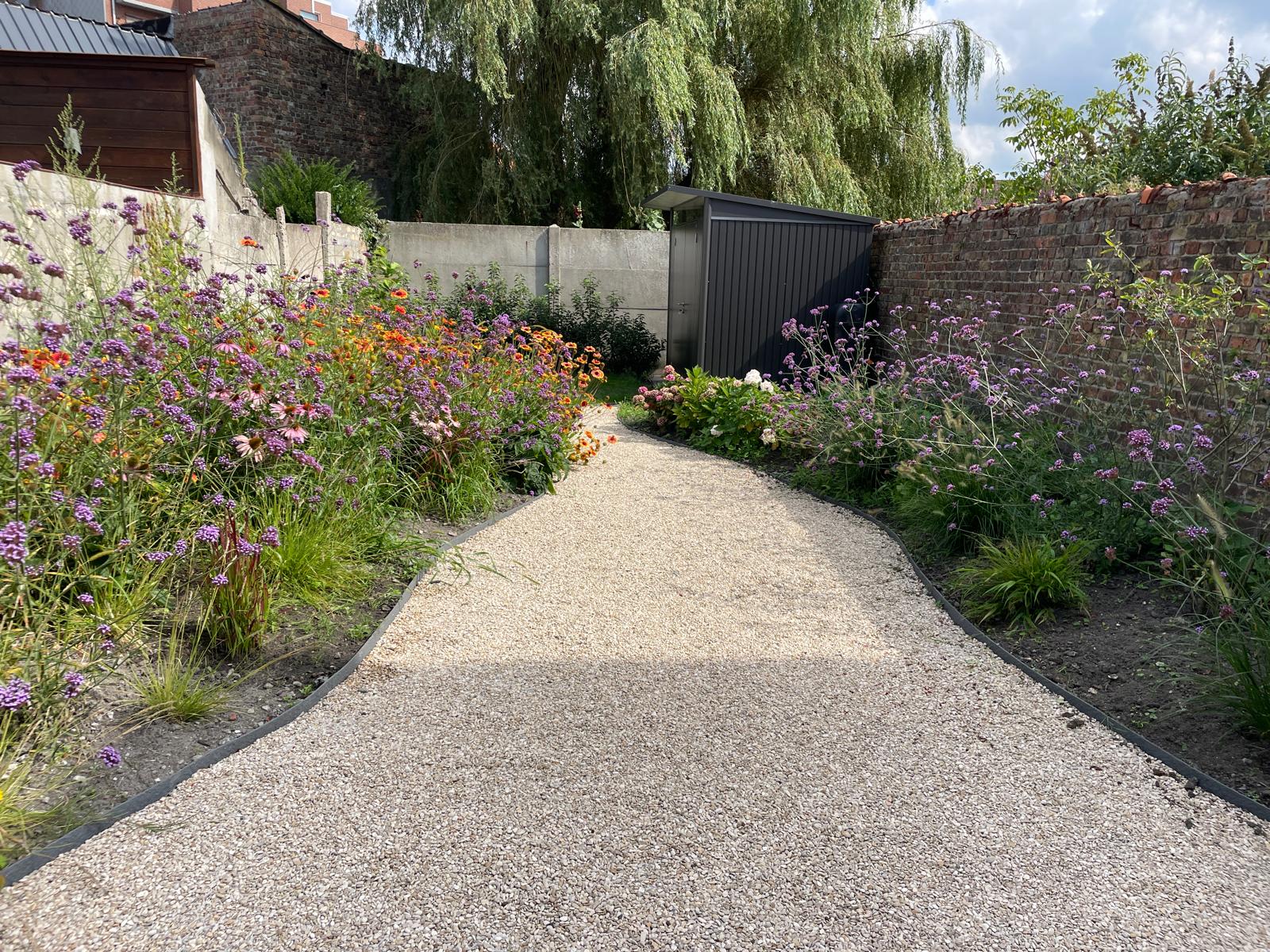 Een luxueuze tuin met een natuurlijke zwemvijver, omgeven door weelderige beplanting en een houten deck, gecreëerd door Intergreen Tuinen.