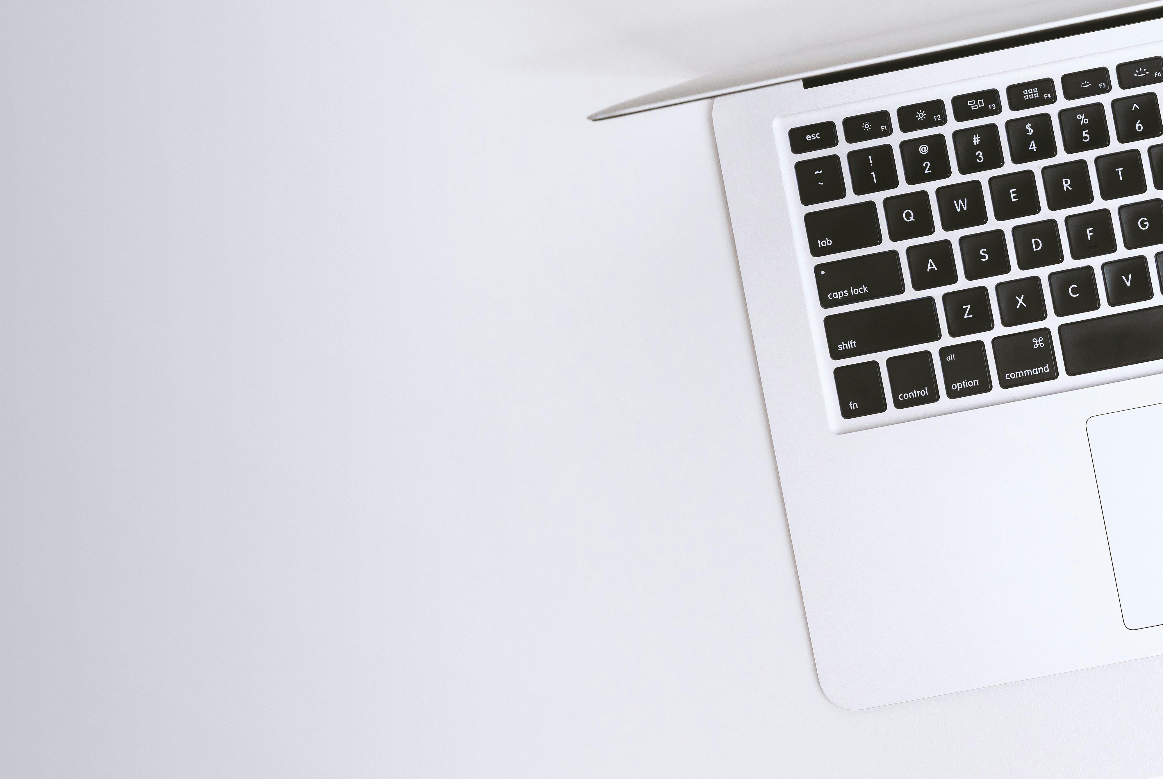 Top view of a sleek laptop keyboard and touchpad on a clean, minimalistic white surface.