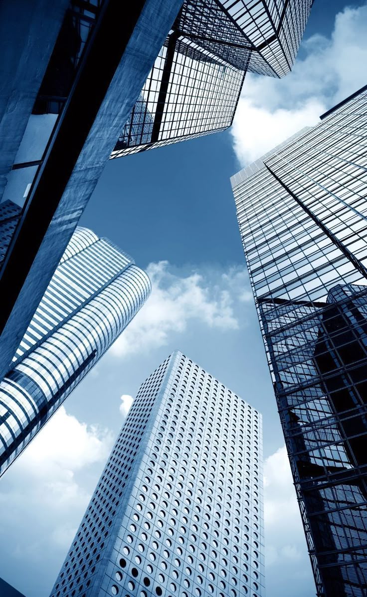 A group of colleagues sitting around a conference table with laptops, listening to a woman leading the meeting in a modern office setting.