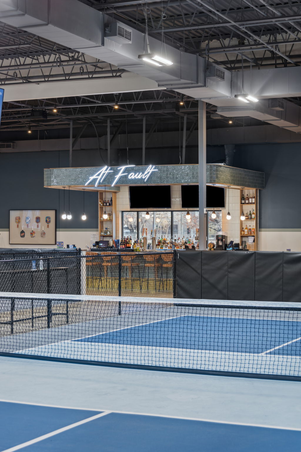 Indoor pickleball courts at At Fault featuring bold interior signage and wayfinding in Dallas, Texas.