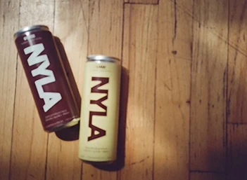 Two NYLA cans laying on a table.