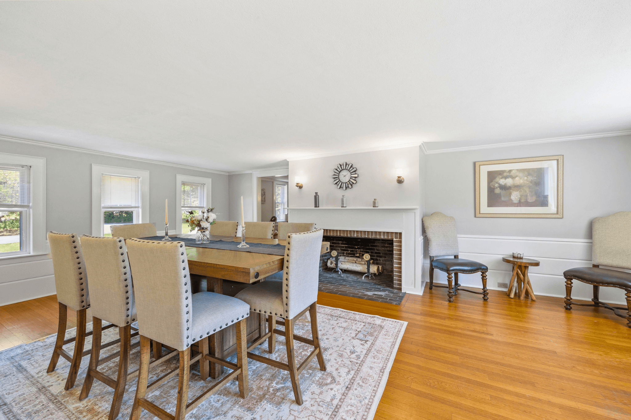 Spacious dining room in Four Winds Estate featuring a large table with tufted chairs, fireplace, and natural light, ideal for hosting group retreats or family gatherings.