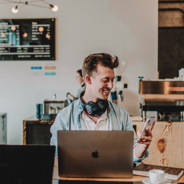 Man sitting at table in coffee shop, working on a laptop