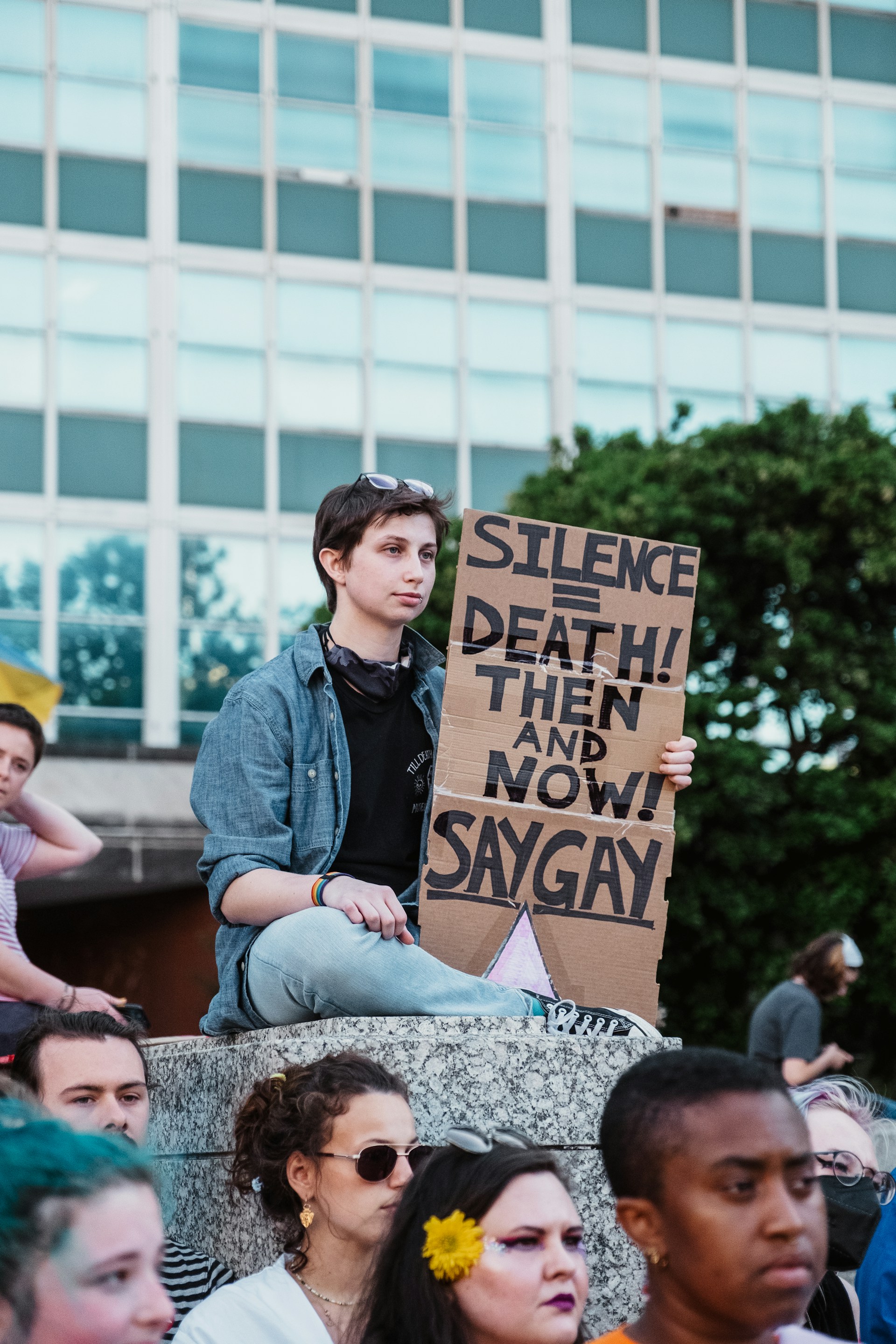 male-read person on a stone holding a sign