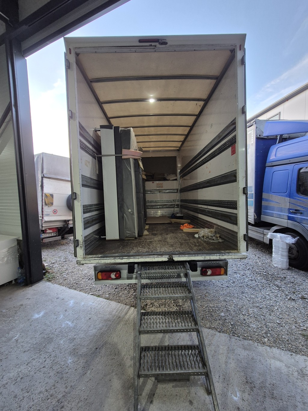 Otvoren kamion za selidbe sa rampom, delimično utovaren nameštajem i kućnim stvarima, spreman za prevoz — profesionalna i bezbedna usluga selidbi u Beogradu.