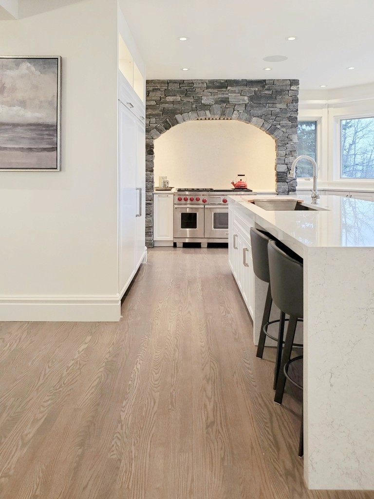 Image of Luxury kitchen design with white cabinetry, marble island, and stone accent wall by KHD Homes.
