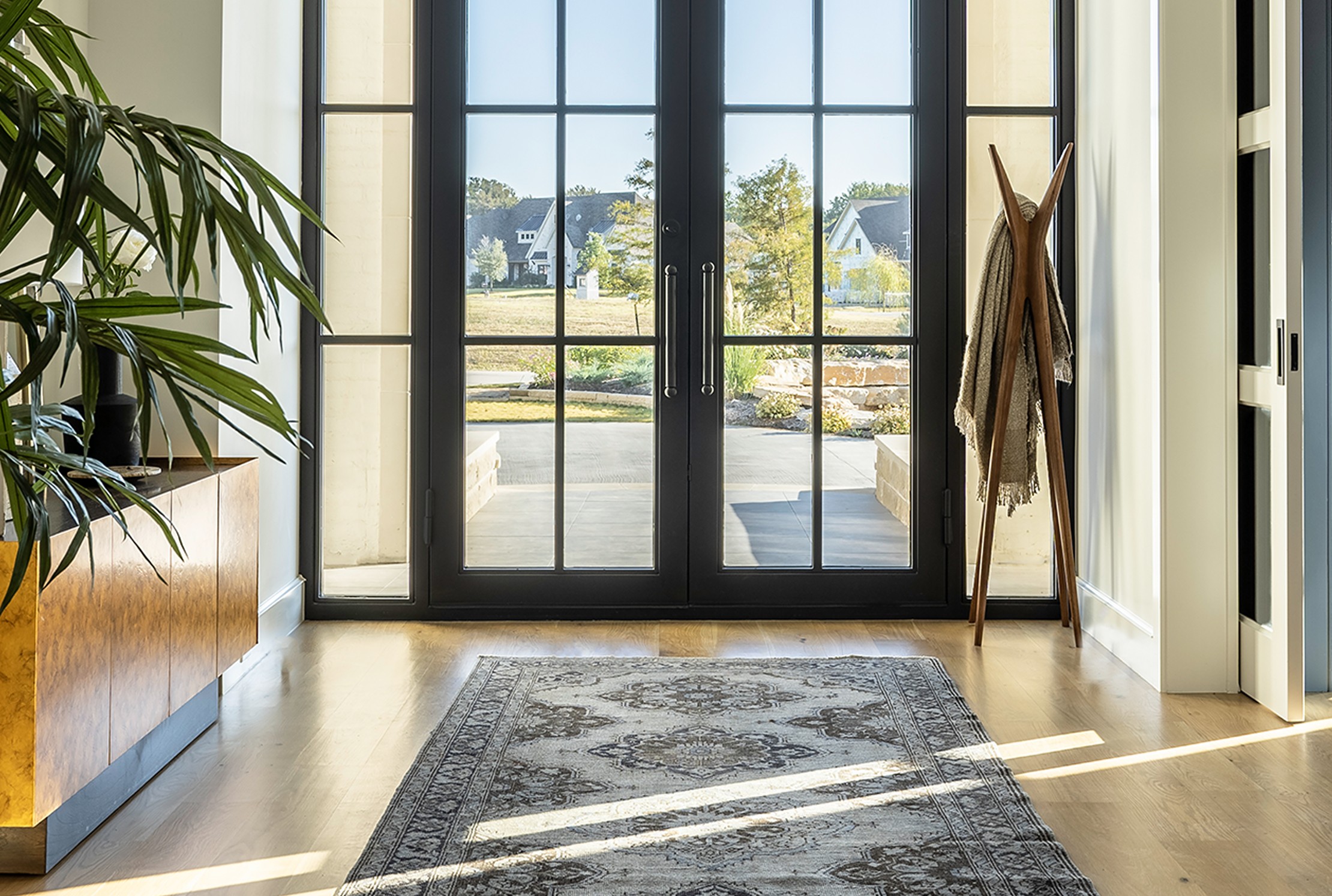Fairview primary suite bedroom with dark walls, modern chandelier, tufted headboard, and seating area by large windows