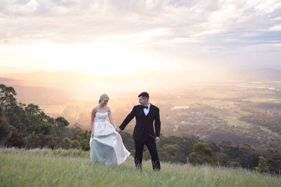 Bride and groom holding hands in front of unset