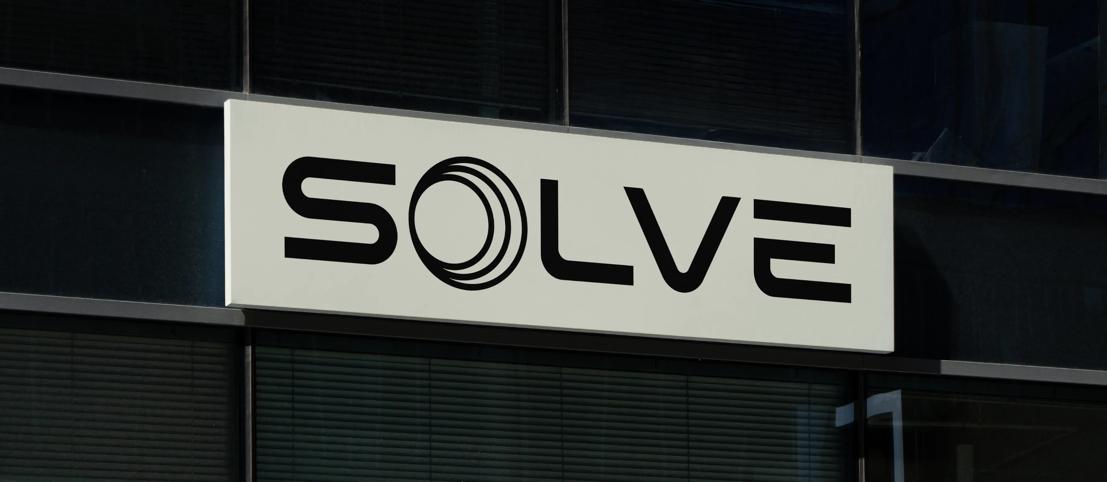 Solve Energy's logo on a sign hanging on the side of a glass building.