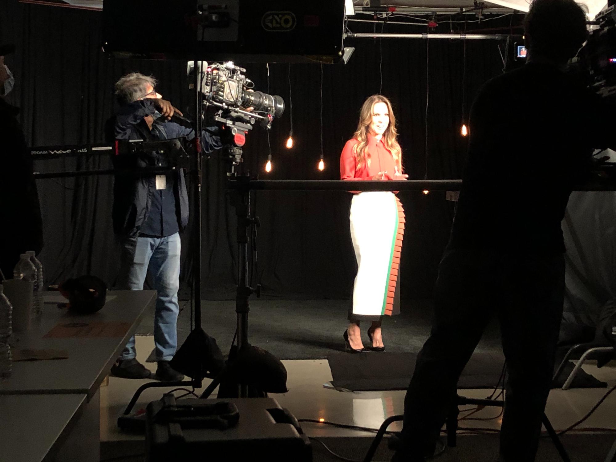 Presenter speaking to camera in a studio setup with cinematic lighting and practical hanging bulbs.