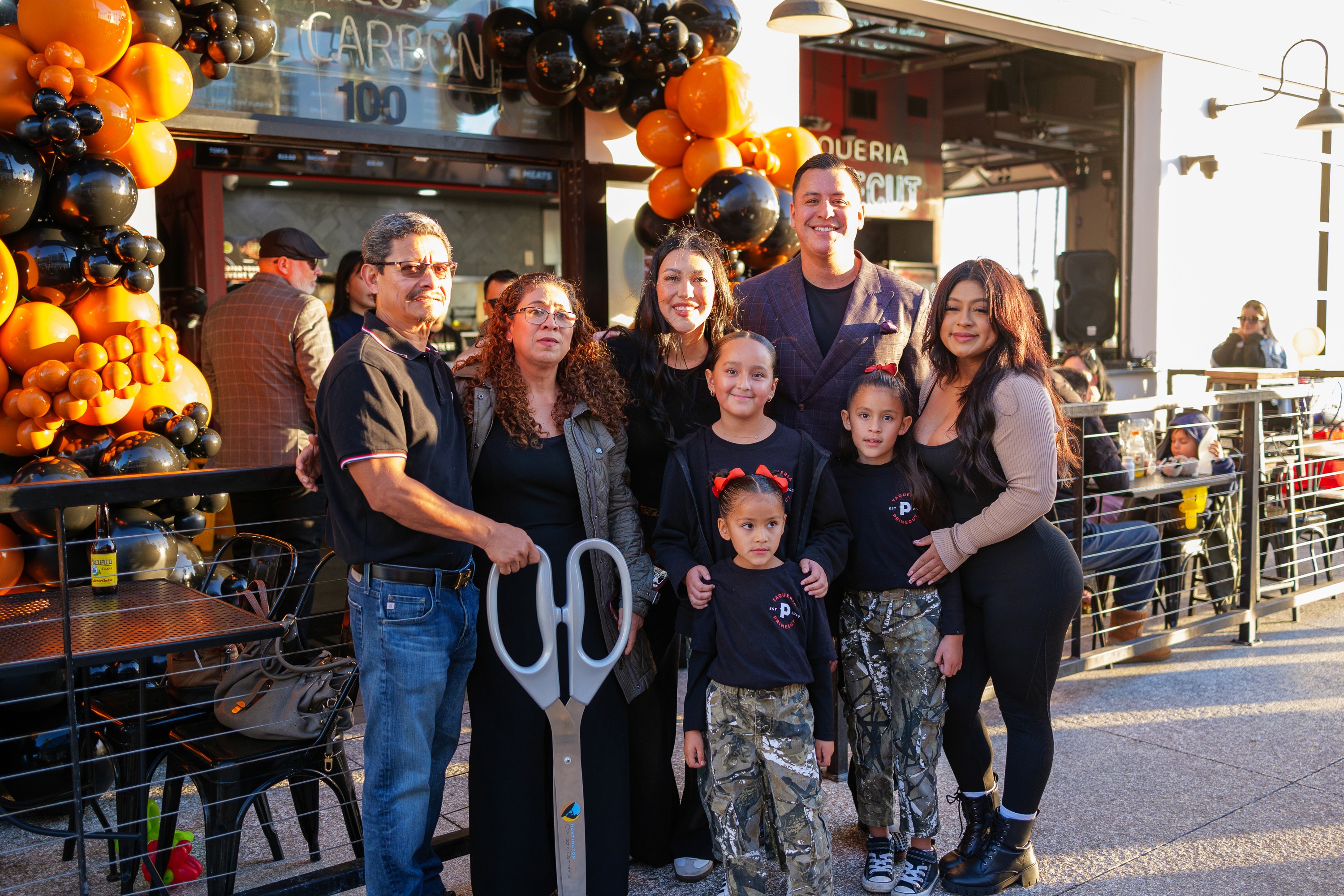 The Primecut family at a restaurant opening with a ribbon-cutting scissors