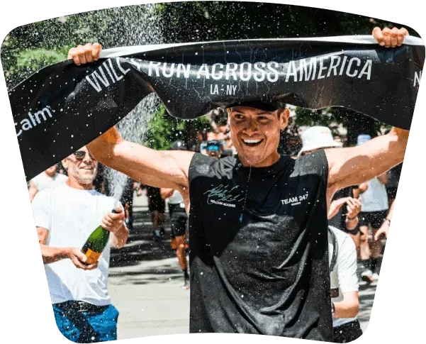 Runner raising a finish banner as people cheer.