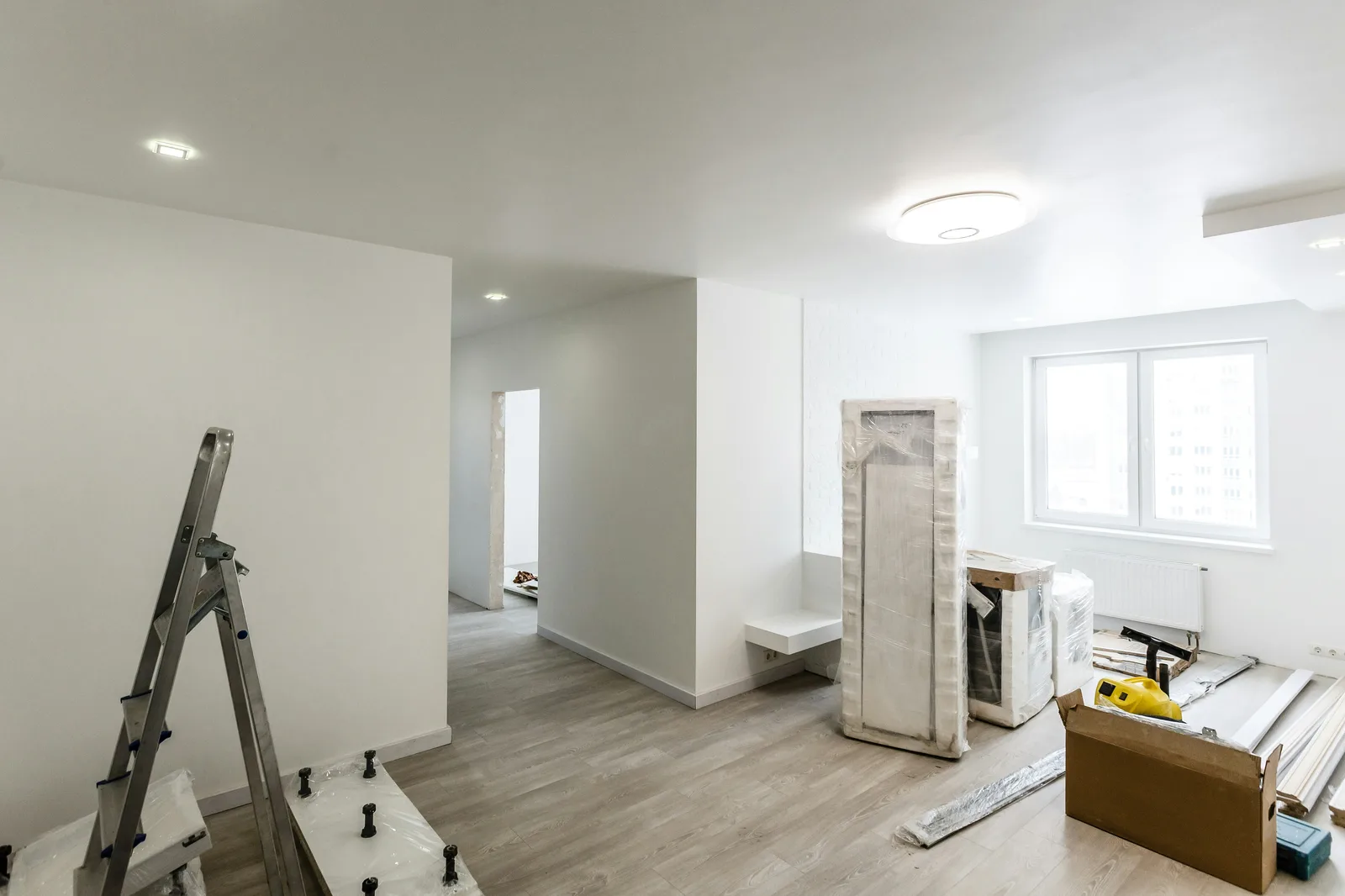 Freshly renovated apartment interior with ladder, tools, and recessed lighting