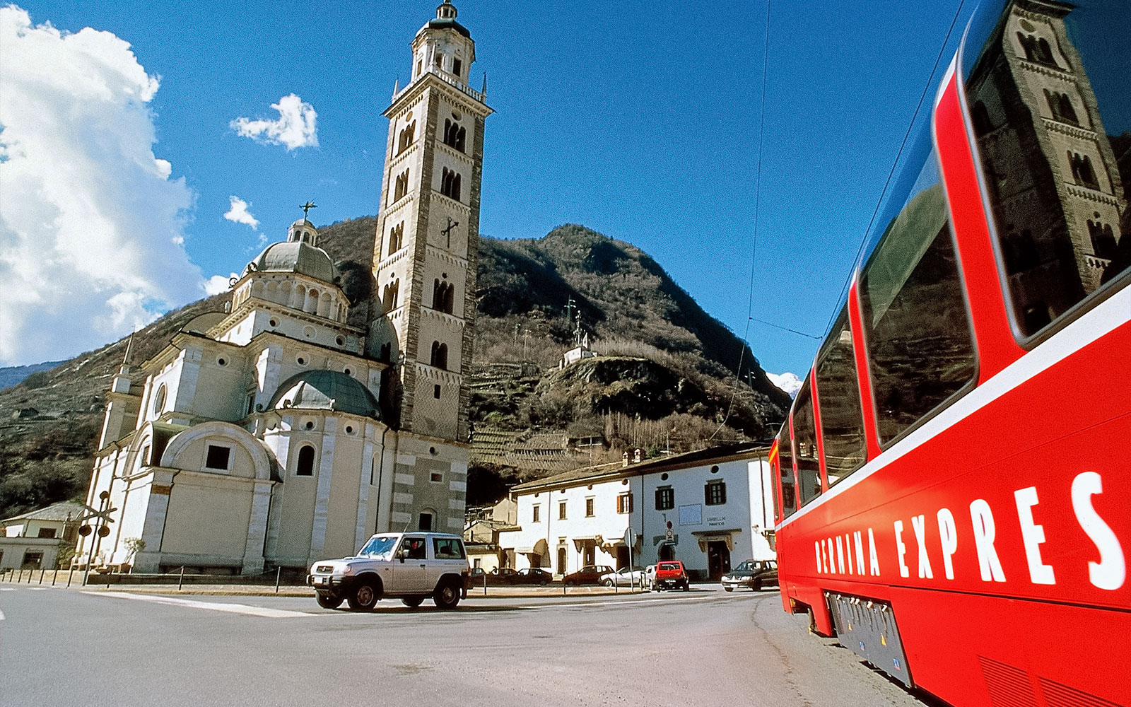 İtalya'nın Tirano kentinde tarihi bir kilisenin yanından geçen Bernina Ekspres treni.