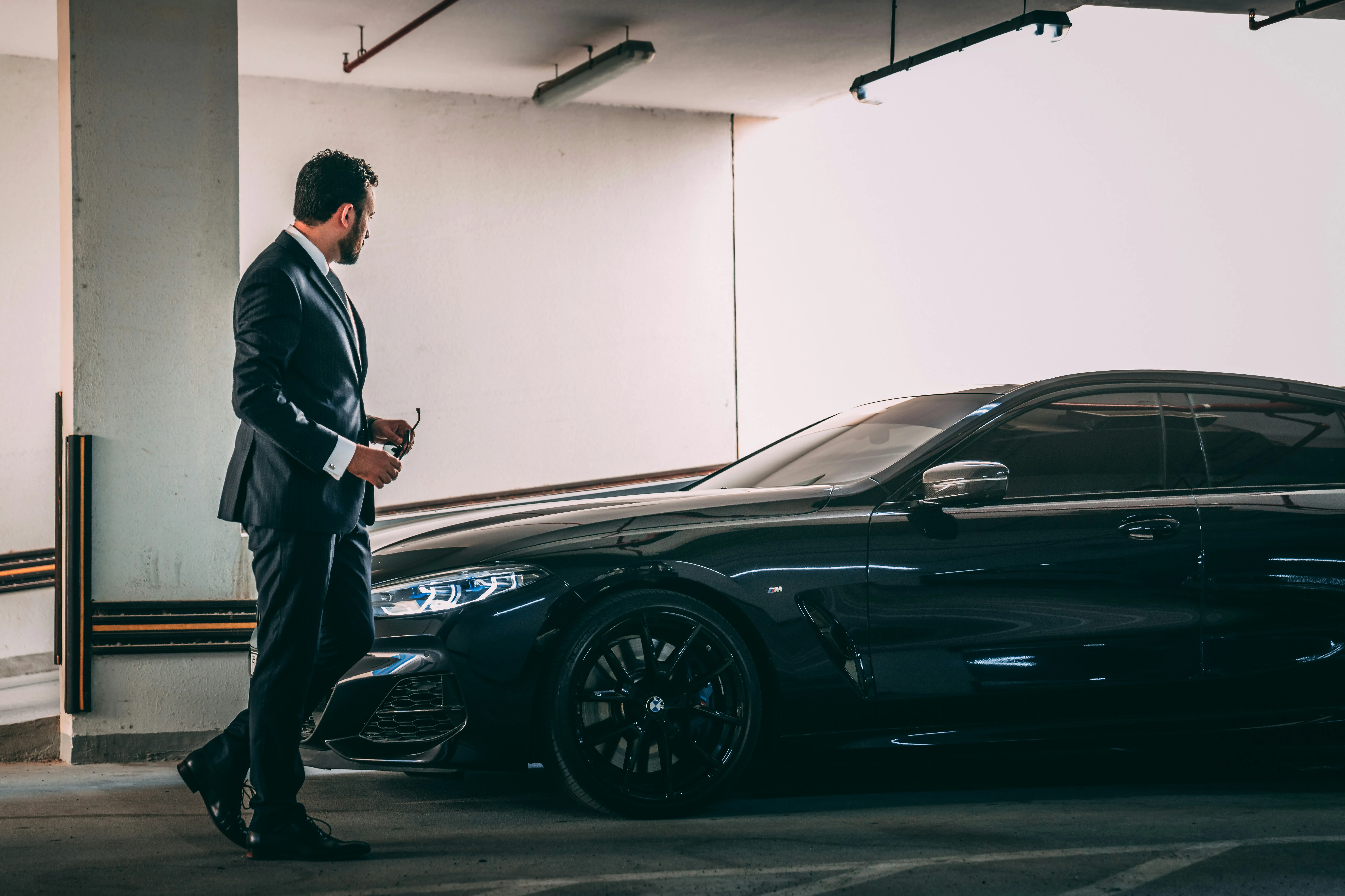 Man in a suit standing next to a black car