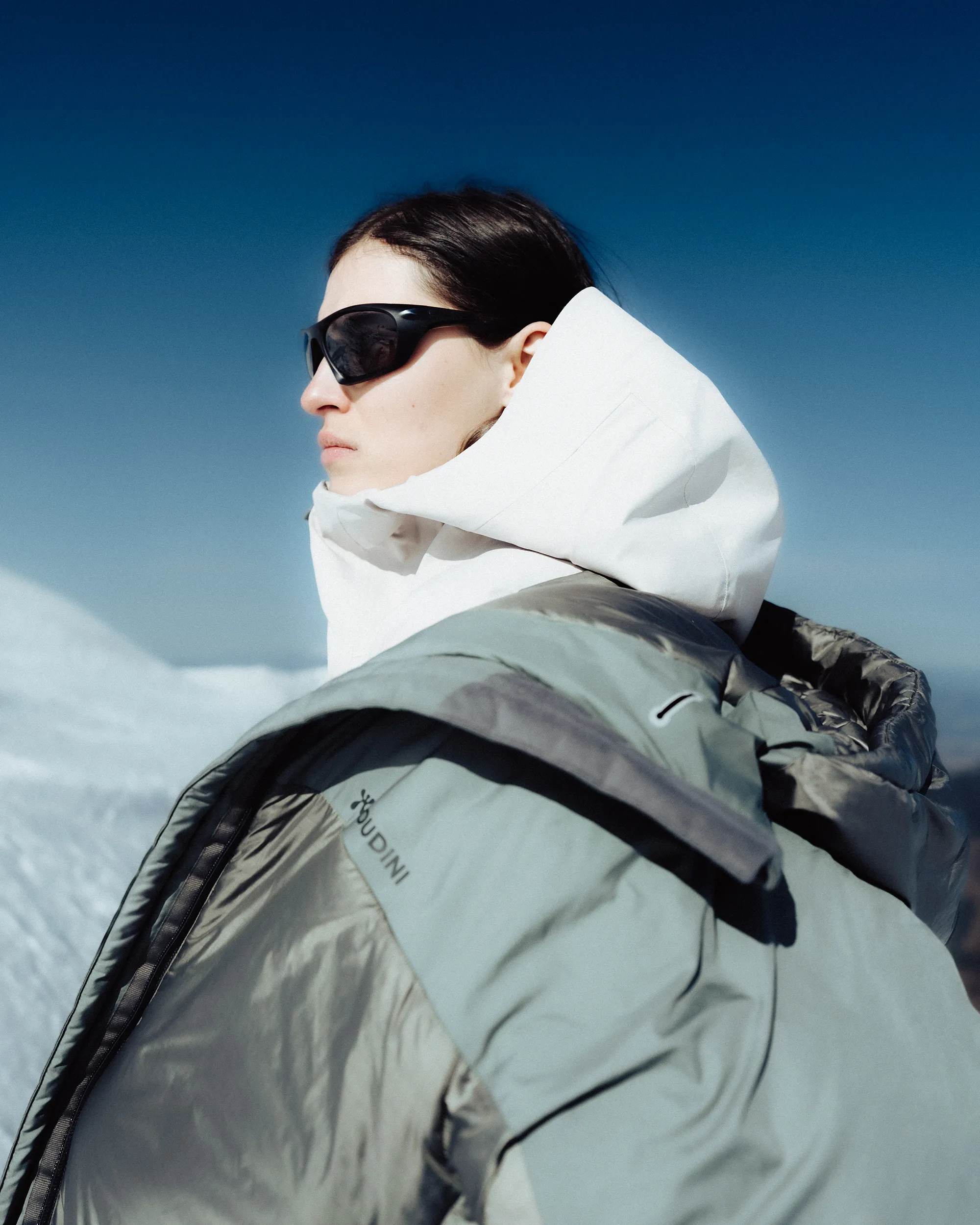 shot of a sport model, skier, in their puffer jacket and sport glasses.