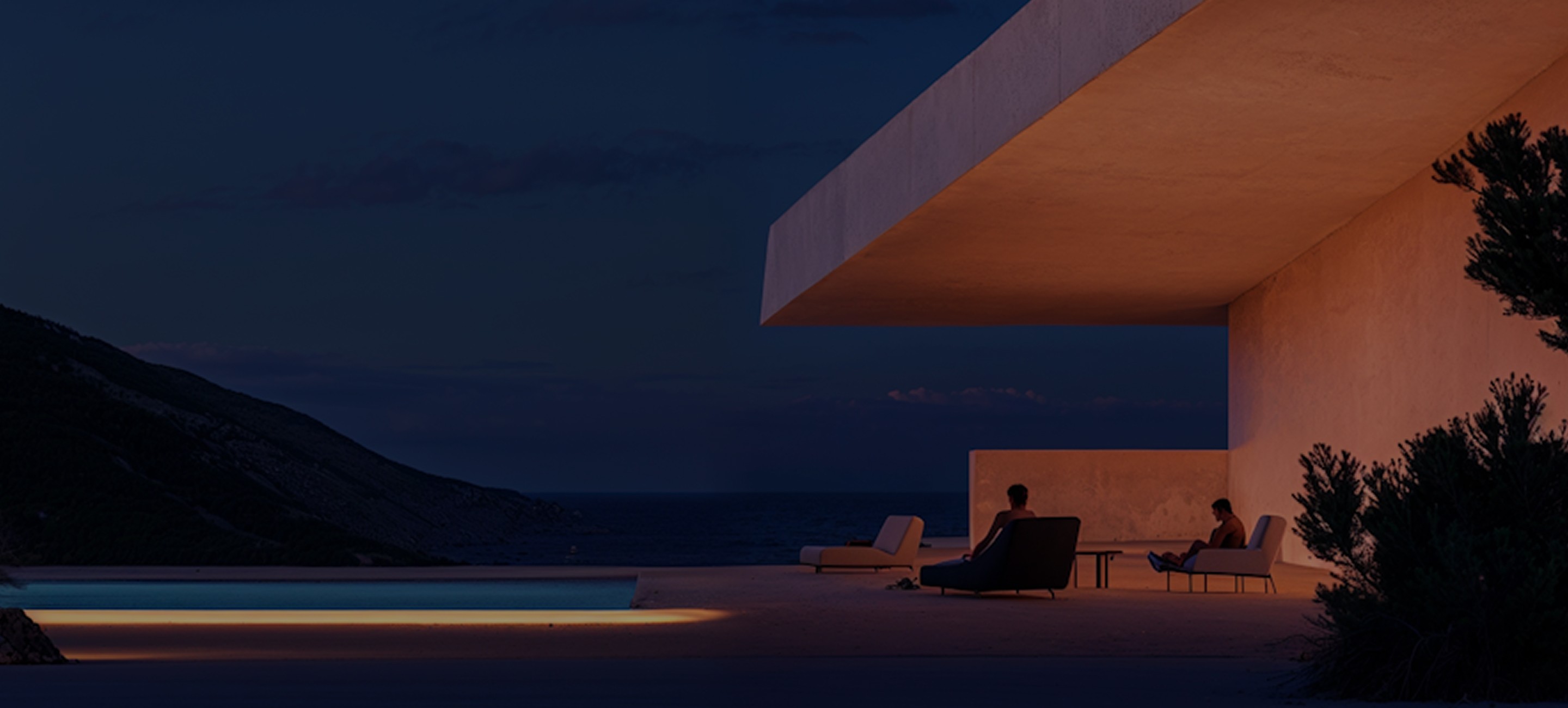 Coastal modern architecture at dusk. Two people lounge by a pool. A third sits under the overhang.