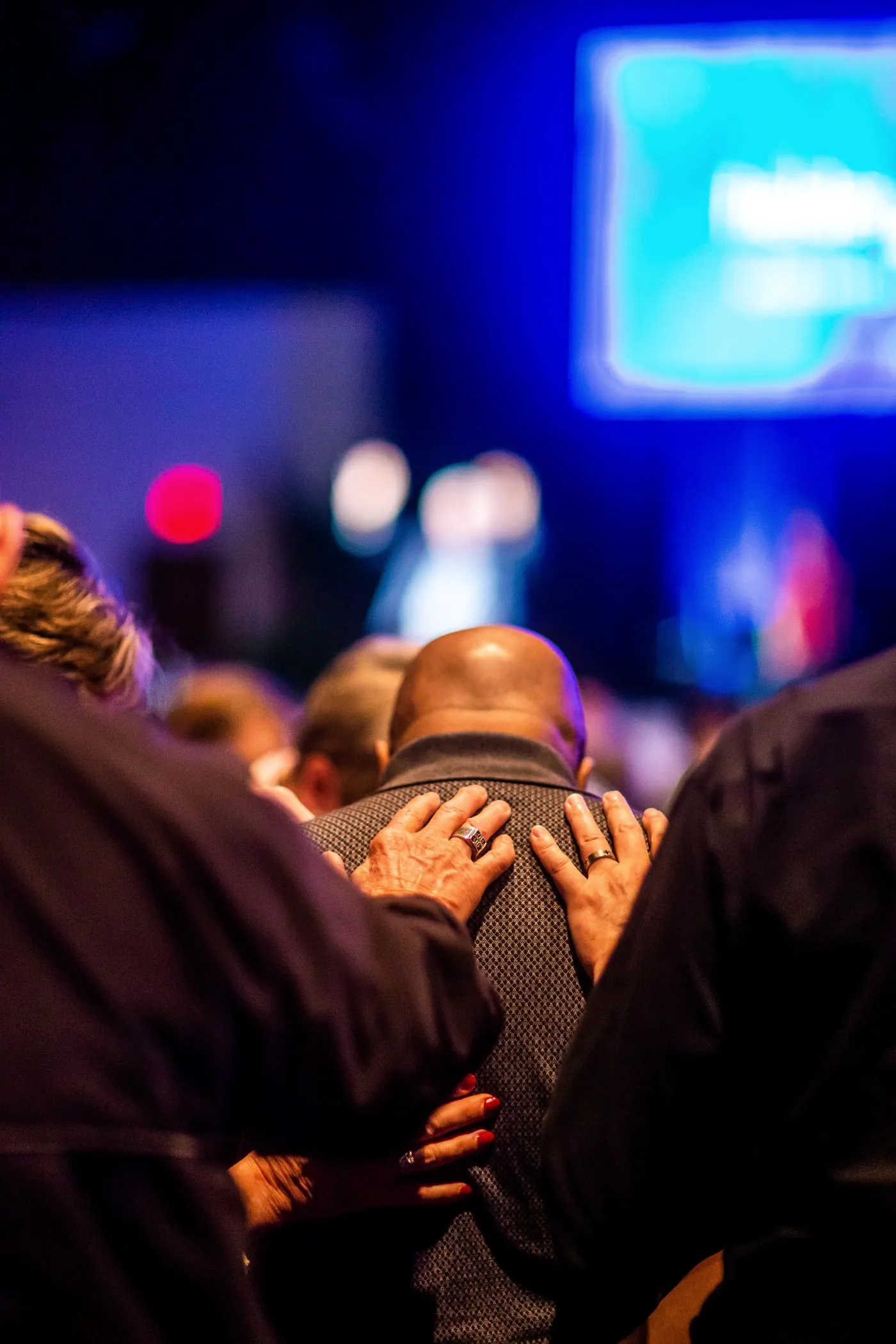 A hand resting on someone’s shoulder in prayer