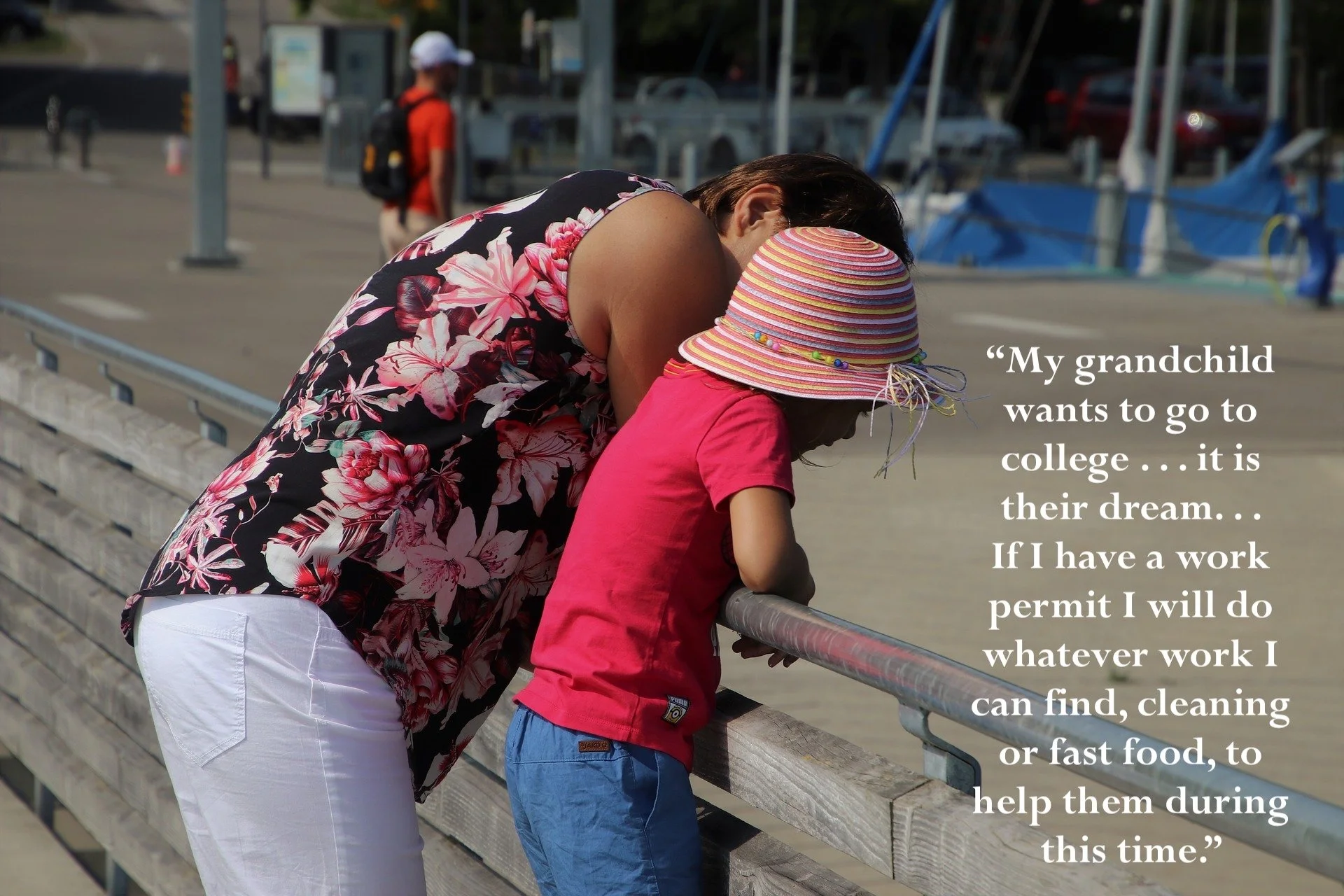 Uma mulher com uma camisa floral se inclina sobre um corrimão de madeira ao lado de uma criança usando um chapéu listrado e uma camisa rosa, com ao fundo uma calçada pavimentada e pessoas; uma sobreposição de texto diz: "Meu neto quer ir para a faculdade... é o sonho dele... Se eu tiver uma autorização de trabalho, farei qualquer trabalho que eu encontrar, limpeza ou fast food, para ajudá-lo durante este período."